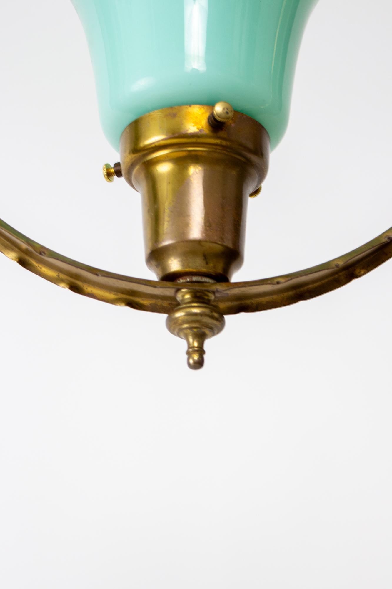 Mid 20th Century hall pendant with turquoise glass. A harp shaped fixture with a round hoop surrounding the light which shines down into an upfacing shade. The socket is hidden by a pressed glass ornamental cup with just peeks out from inside the
