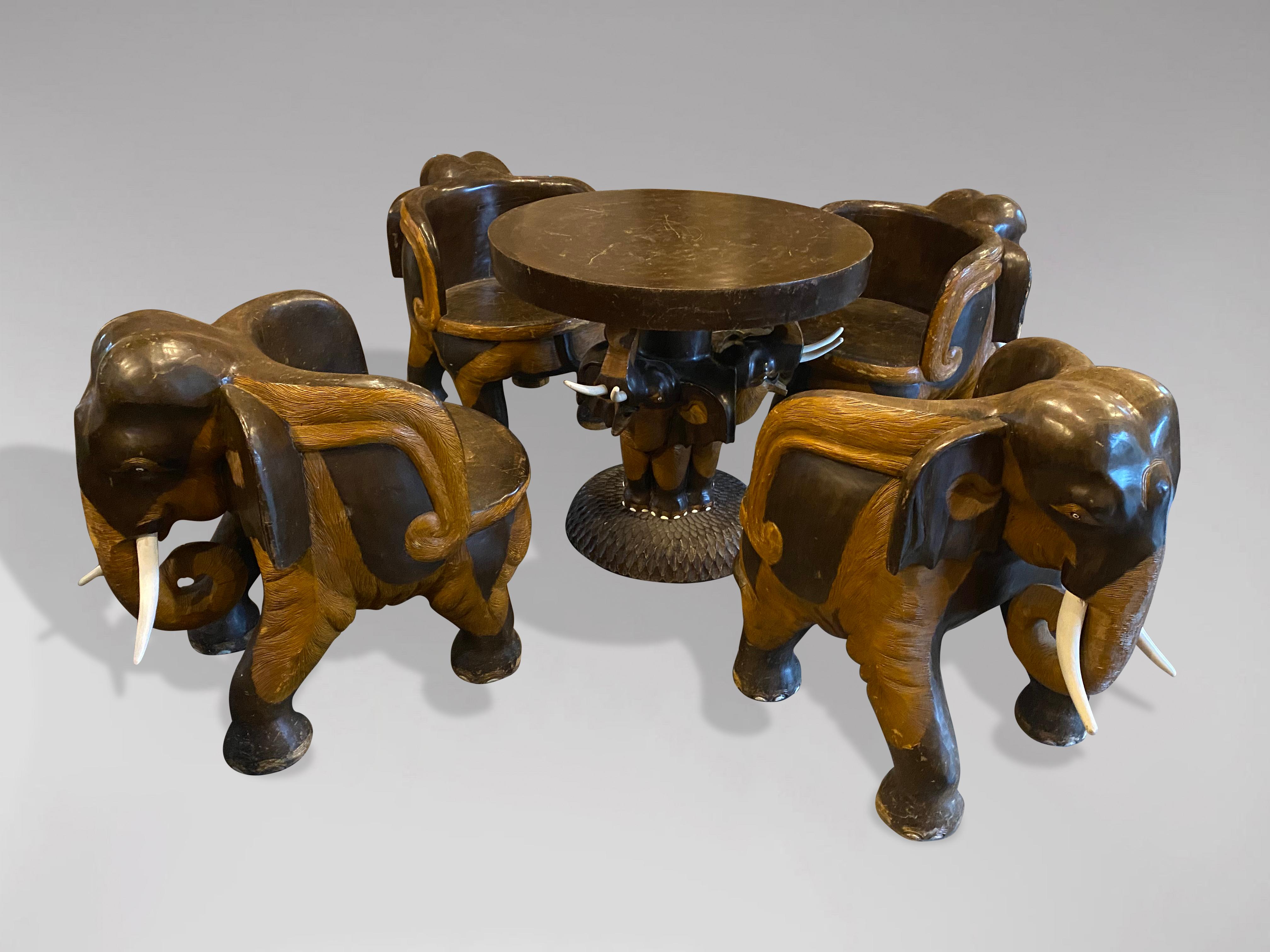 A stunning mid 20th century Anglo Indian vintage hand carved hardwood living room set. Comprising a set of 4 tub armchairs and a circular table, hand carved and modelled as a standing elephant. Each chair is hand carved from a single piece of