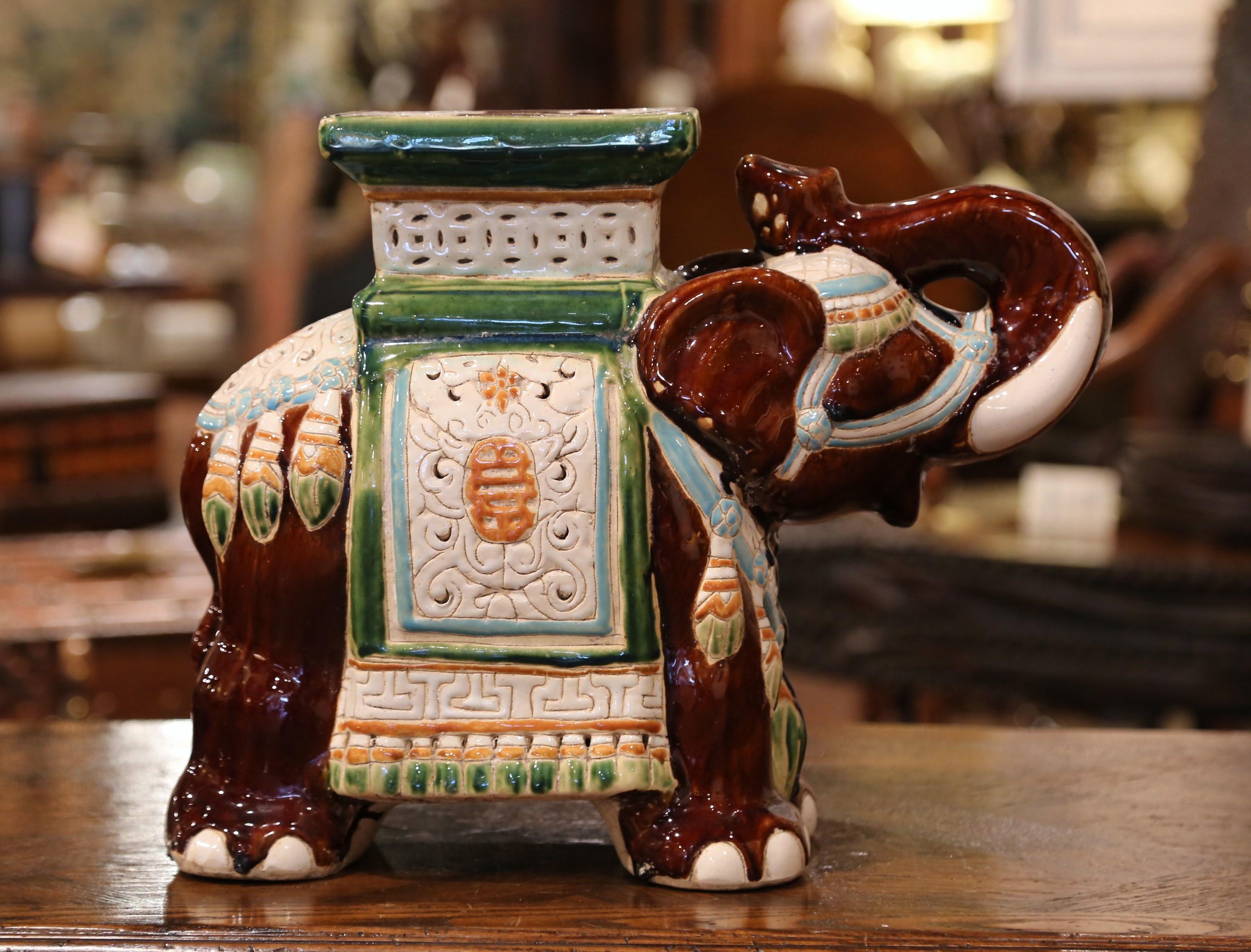 This interesting, vintage porcelain garden seat was found in France. Crafted circa 1960, the ceramic seating shaped as an elephant with his trunk raised (good luck sign in Asia), is heavily decorated in oriental finery; the colorful mammal has a