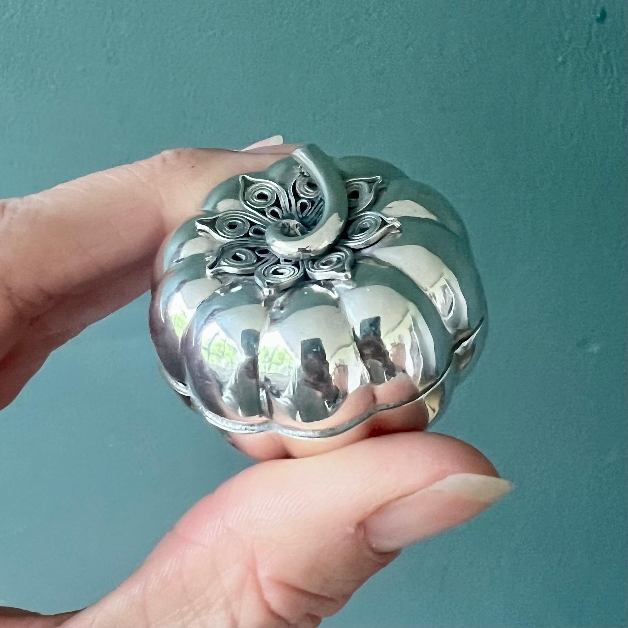 This charming vintage box is beautifully handcrafted in the shape of a stylized pumpkin, made from sterling silver with a softly polished surface that enhances its sculptural form. The piece features a gently curved stem handle and an intricately