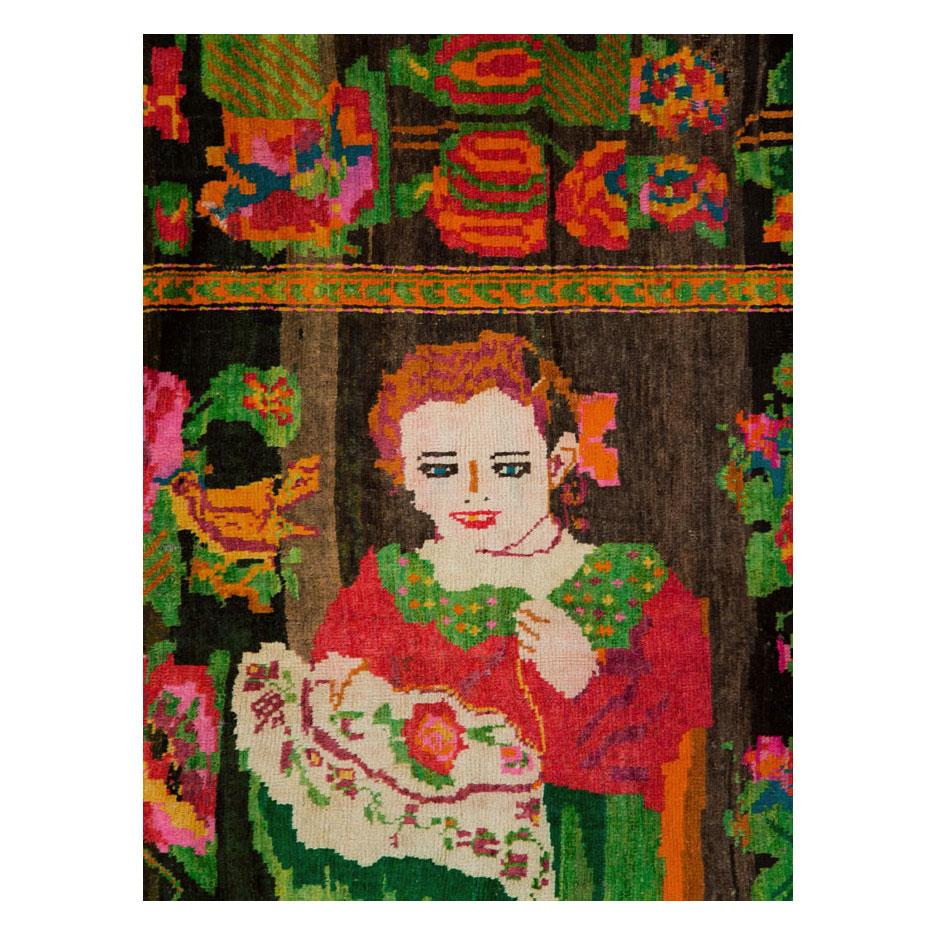 Tappeto vintage del Karabagh caucasico realizzato a mano a metà del XX secolo con un disegno pittorico di due donne che cuciono circondate da bouquet floreali europei in verde, rosa, rosso, arancione e blu su uno sfondo nero e marrone