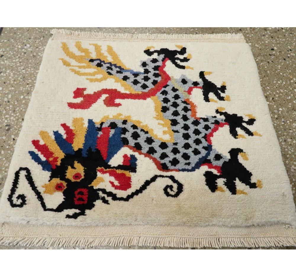 A vintage Chinese Art Deco throw rug handmade during the mid-20th century with a pictorial design of a dragon in black, blue, red, goldenrod, and light blue-grey over a cream-white borderless field.

Measures: 1' 3