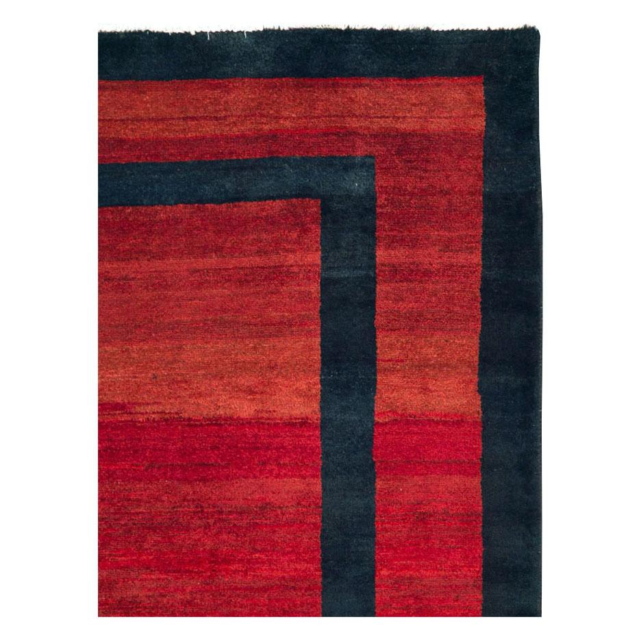 A vintage Persian Mahal accent rug in the Art Deco style handmade during the mid-20th century with a solid red field and border divided by solid dark blue graphic lines that read dark blue from the light side and black from the dark side of the