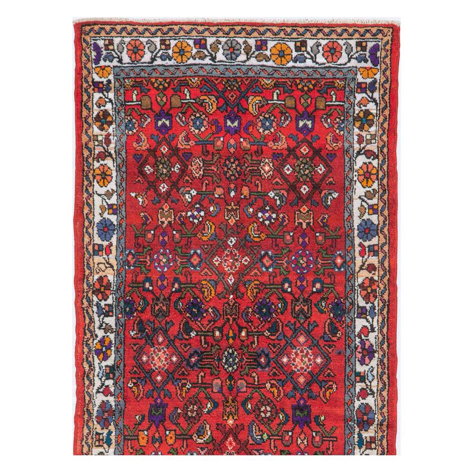 A vintage Persian Hamadan rug in runner format handmade during the mid-20th century with the traditional Persian 'Herati' pattern over a red field. The overall aesthetic is quite bright and vivid.

Measures: 2' 7