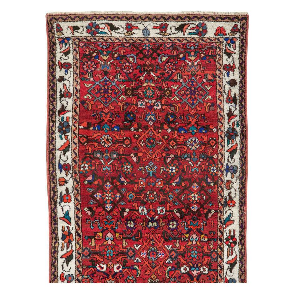 A vintage Persian Hamadan rug in runner format handmade during the mid-20th century with the traditional Persian 'Herati' pattern over a red field. The overall aesthetic is quite bright and vivid.

Measures: 2' 8