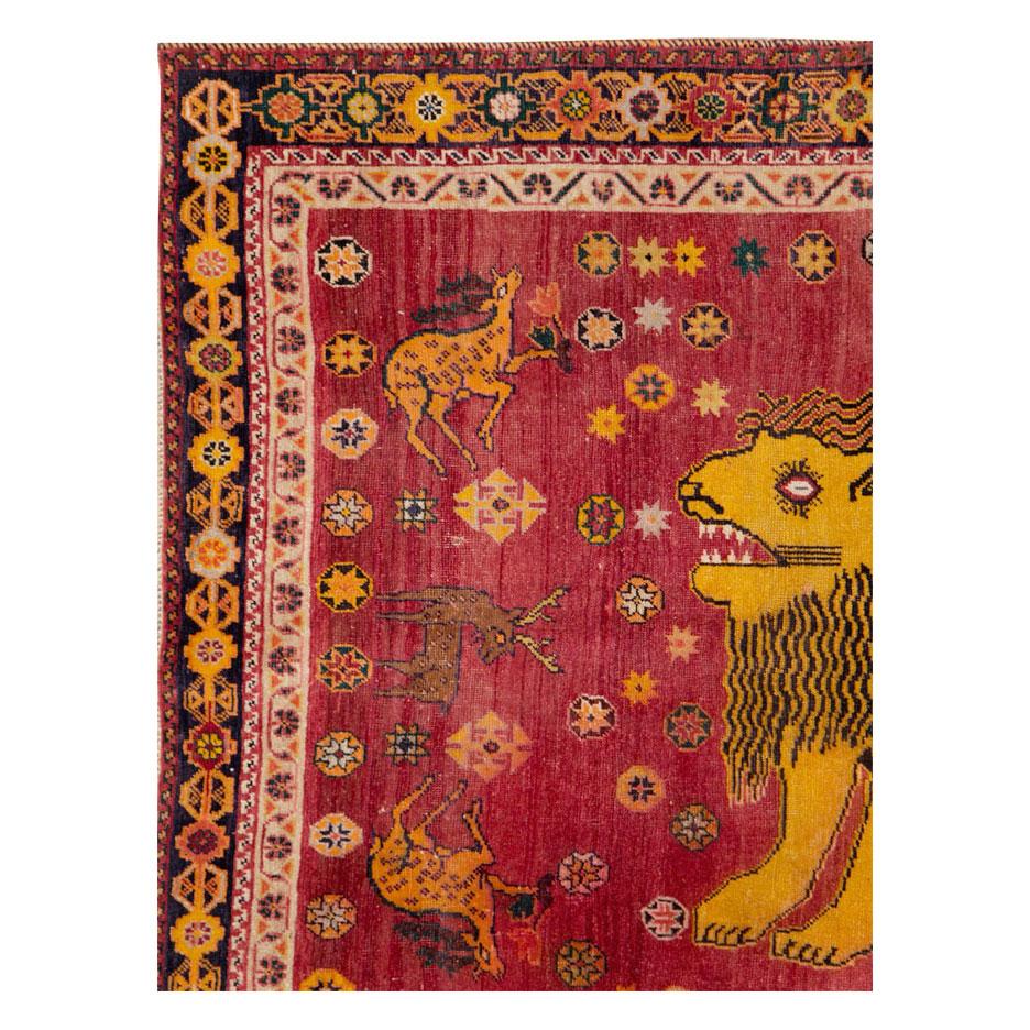 A vintage Persian Shiraz accent rug handmade during the mid-20th century with a pictorial design of a large yellow lion over a ruby red field decorated by several randomized animal figures.

Measures: 4' 11