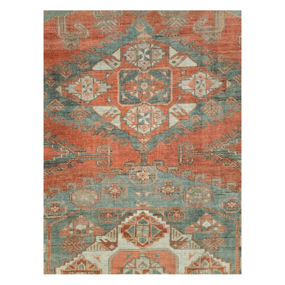A vintage Persian Veece room size carpet handmade during the mid-20th century with a large and geometric medallions in slate grey over a rust red field. Hints of light blue are seen throughout including on the main border.

Measures: 8' 10