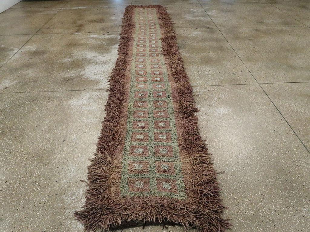 Un tapis tibétain vintage au format d'un tapis de course, fabriqué à la main au milieu du 20e siècle.

Mesures : 2' 6