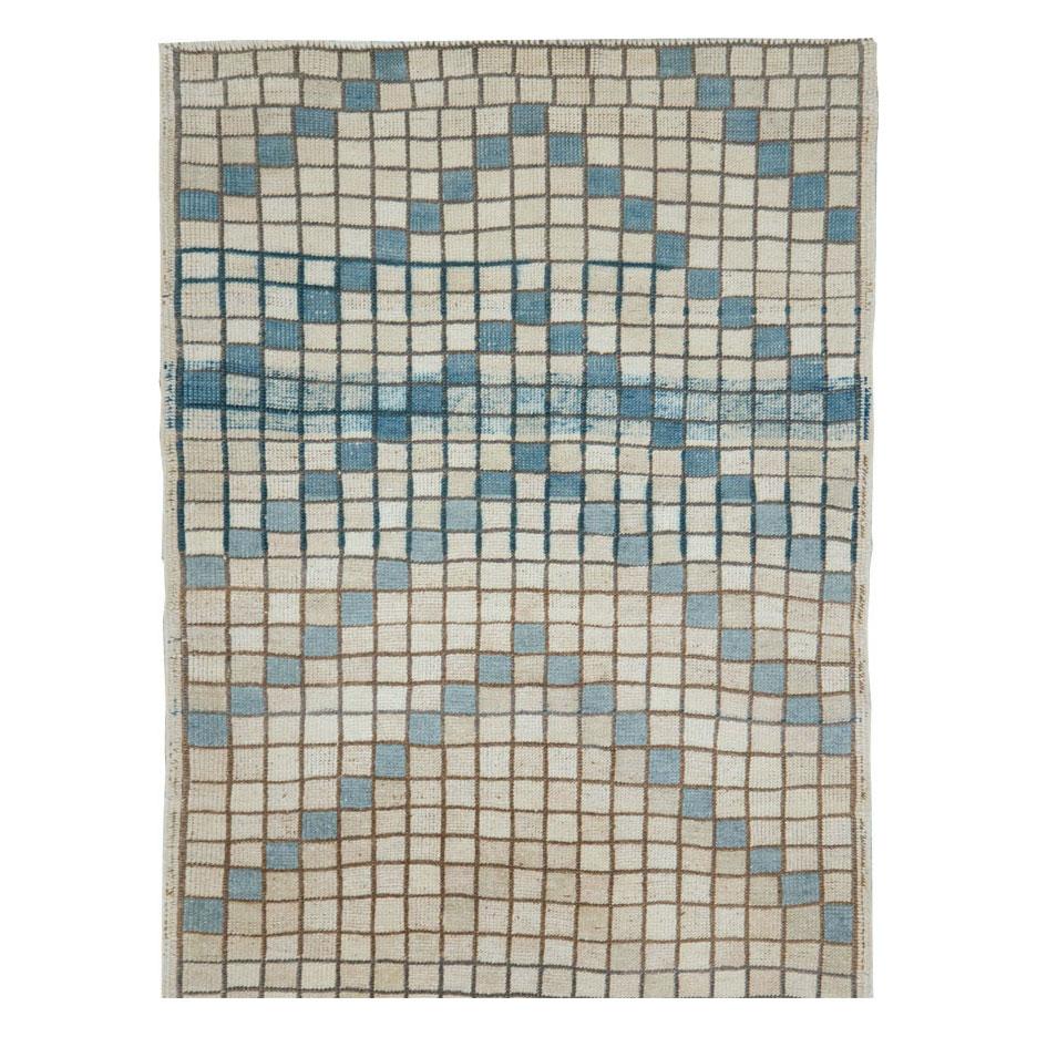 A vintage Turkish Anatolian modernist small rug in runner format handmade during the mid-20th century in shades of cream, light blue, and blue grey.