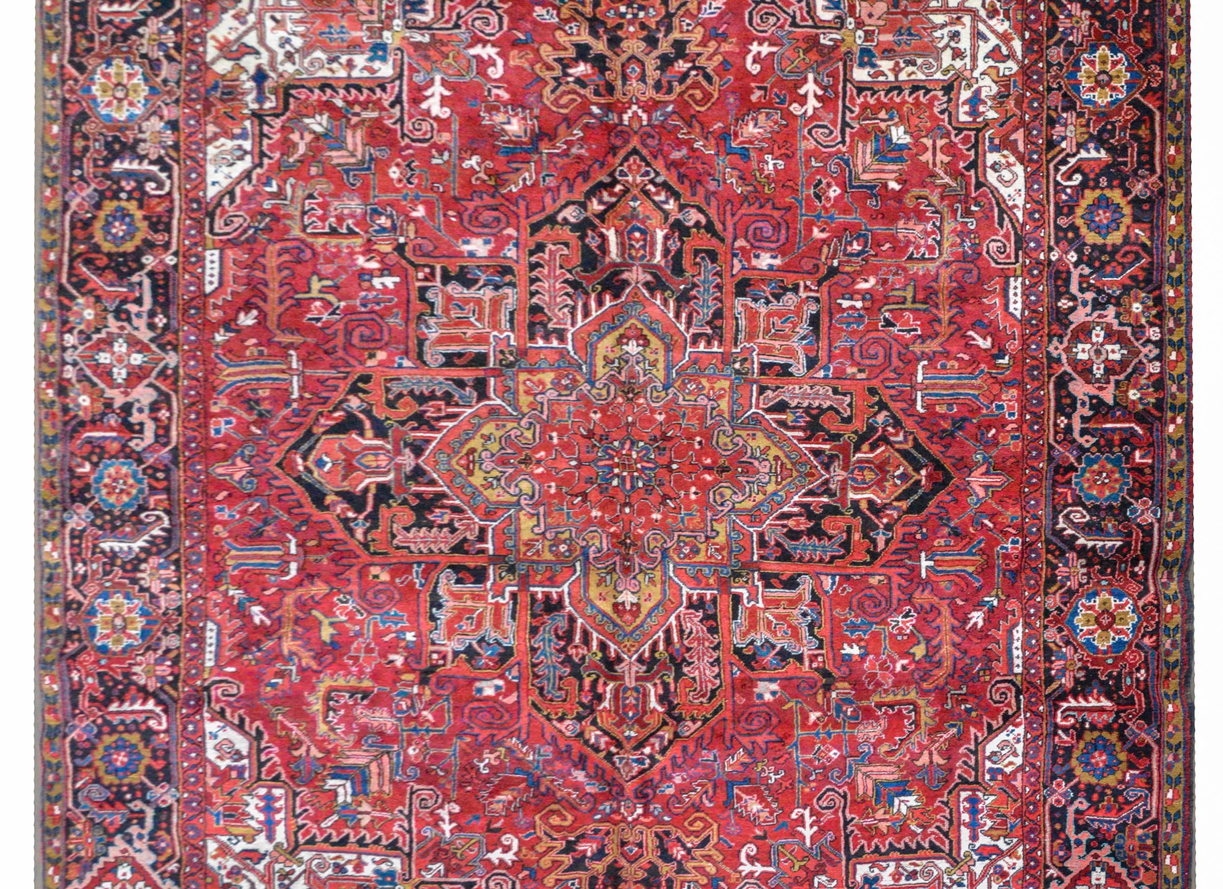 A wonderful mid-20th century Persian Heriz rug with a traditional large-scale stylized floral medallion woven in myriad colors and set against a tightly woven field of flowers and leaves, and surrounded by a wide border containing more large and