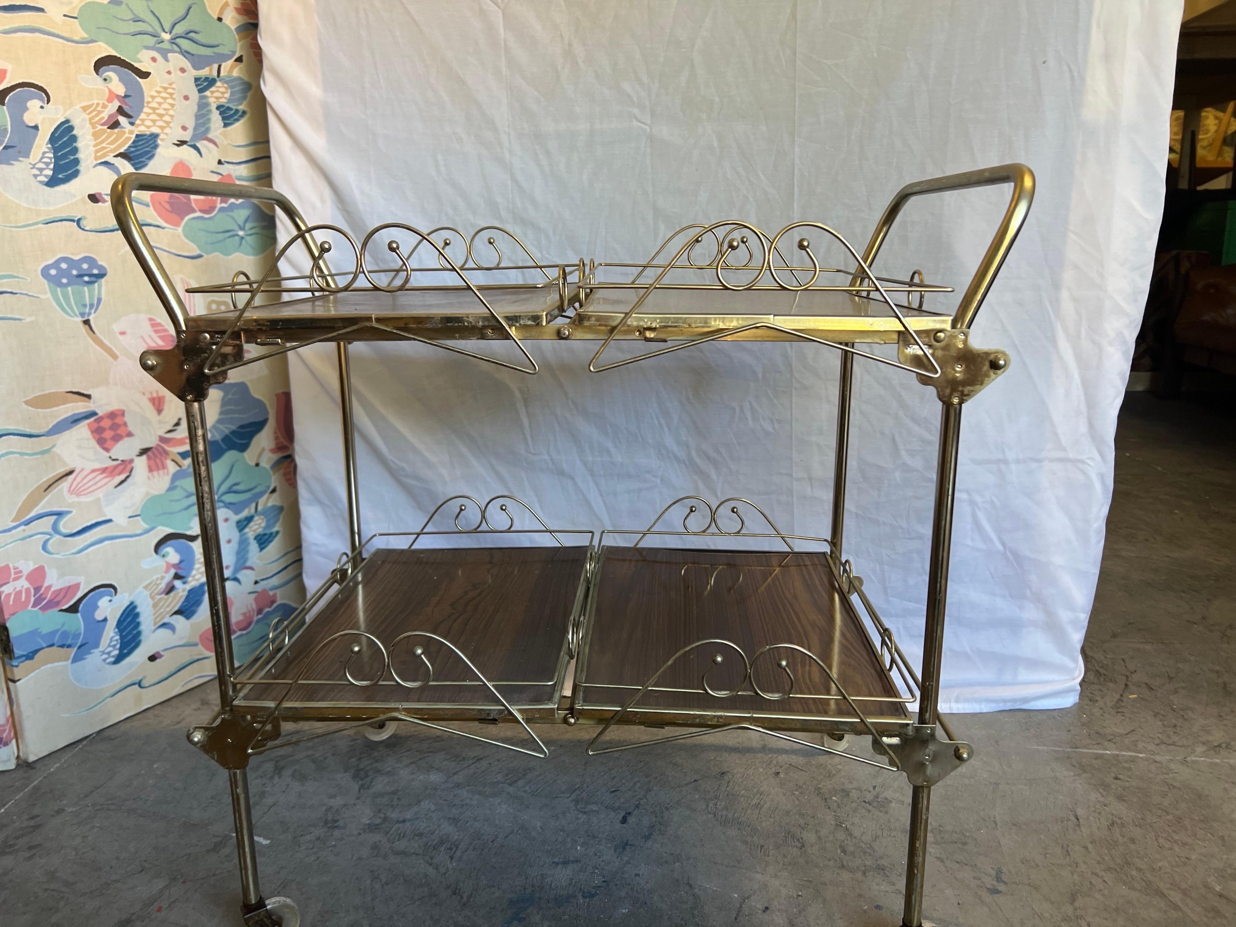This fantastic bar cart has a beautifully scrolled details and double brass toned handles.   Original lucite wheels still function very well.   The Formica walnut grained trays are all removable and the base has a locking mechanism for when in use. 