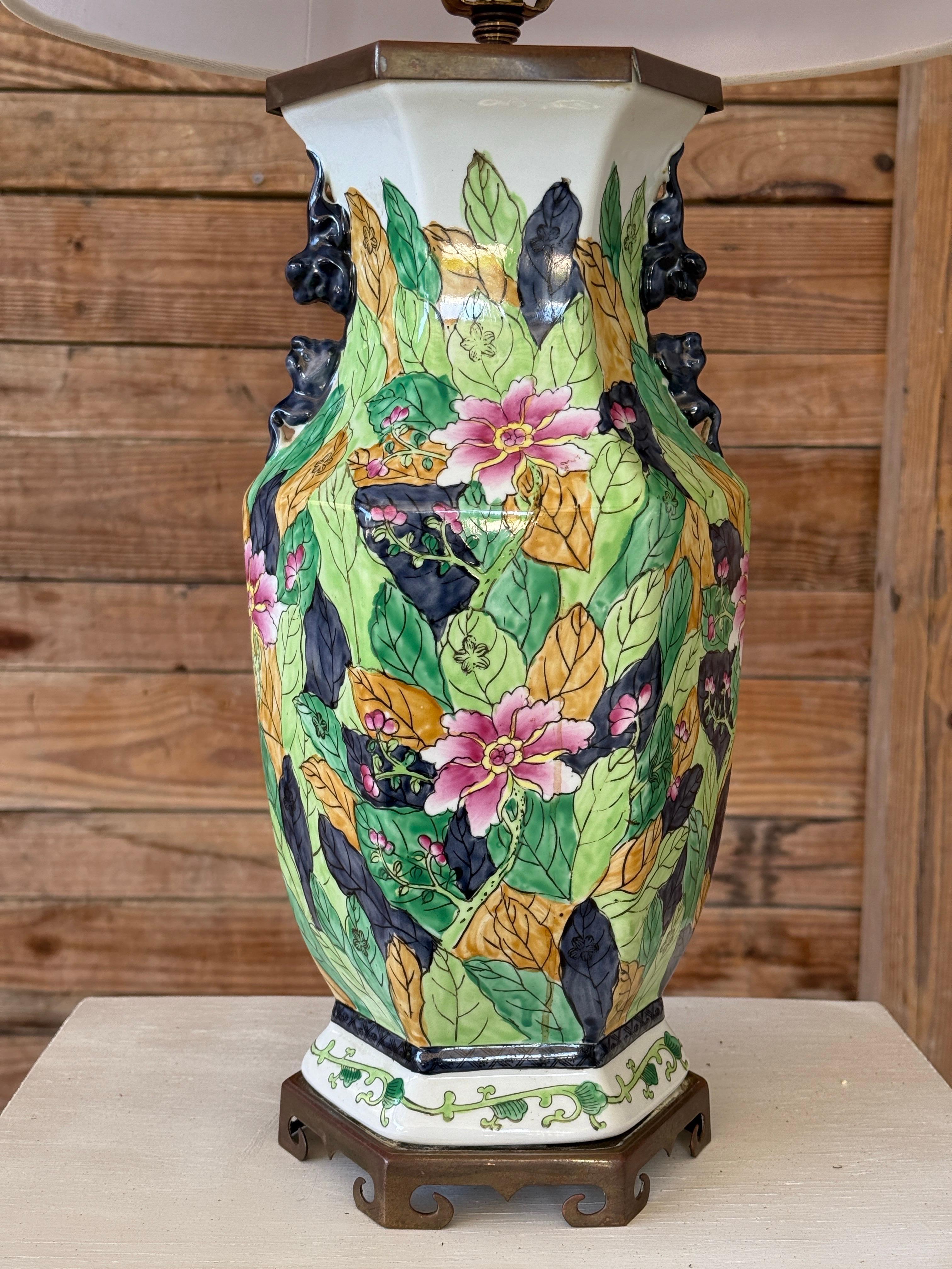 Lampe de table en porcelaine du milieu du 20e siècle présentant le motif emblématique Tobacco Leaf - un motif richement peint à la main de feuilles et de fleurs tropicales dans des tons audacieux de vert, de bleu marine et d'or avec des fleurs roses