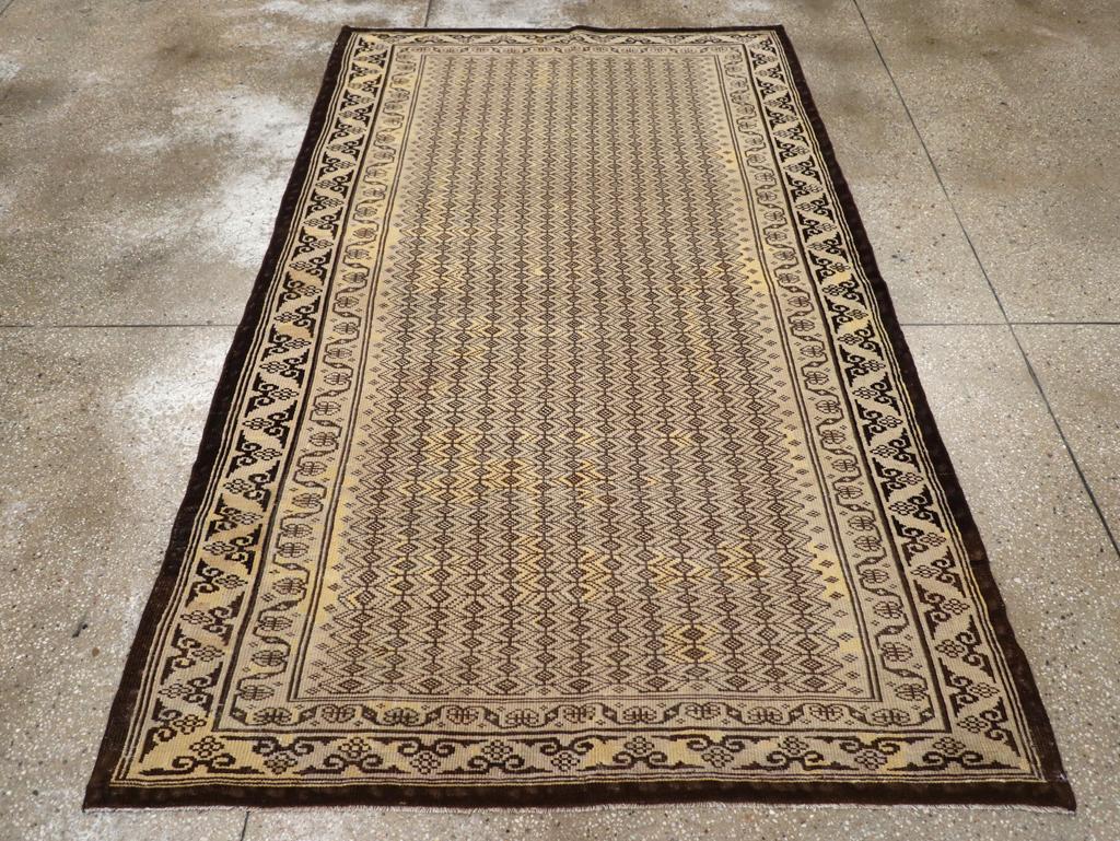 A vintage Indian Agra accent rug. Thousands of tiny lozenges are set within a connected small hexagon lattice on the variegated beige field of this northern Indian urban rug. The main border of ram’s horns triangles, also on beige, makes an unusual