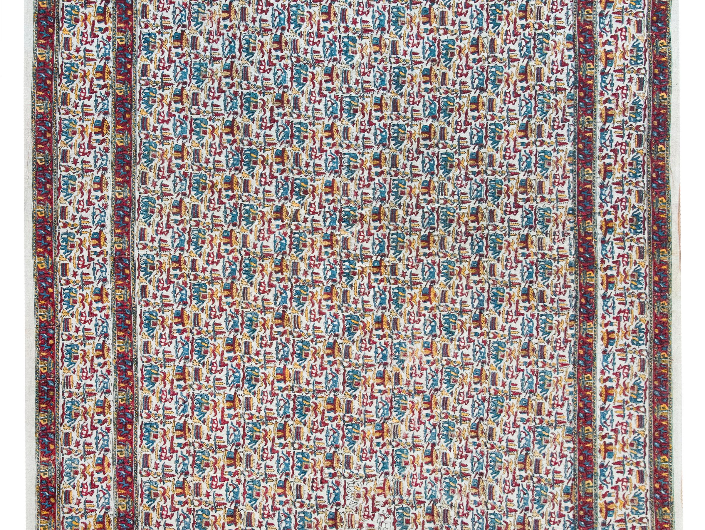 This charming mid-20th century Indian cotton textile bursts with retro personality, hand-woven and hand-block printed in a playful, folksy pattern of elephants, deer, lions, human figures, and huts. Rendered in bold primary colors—red, blue, and