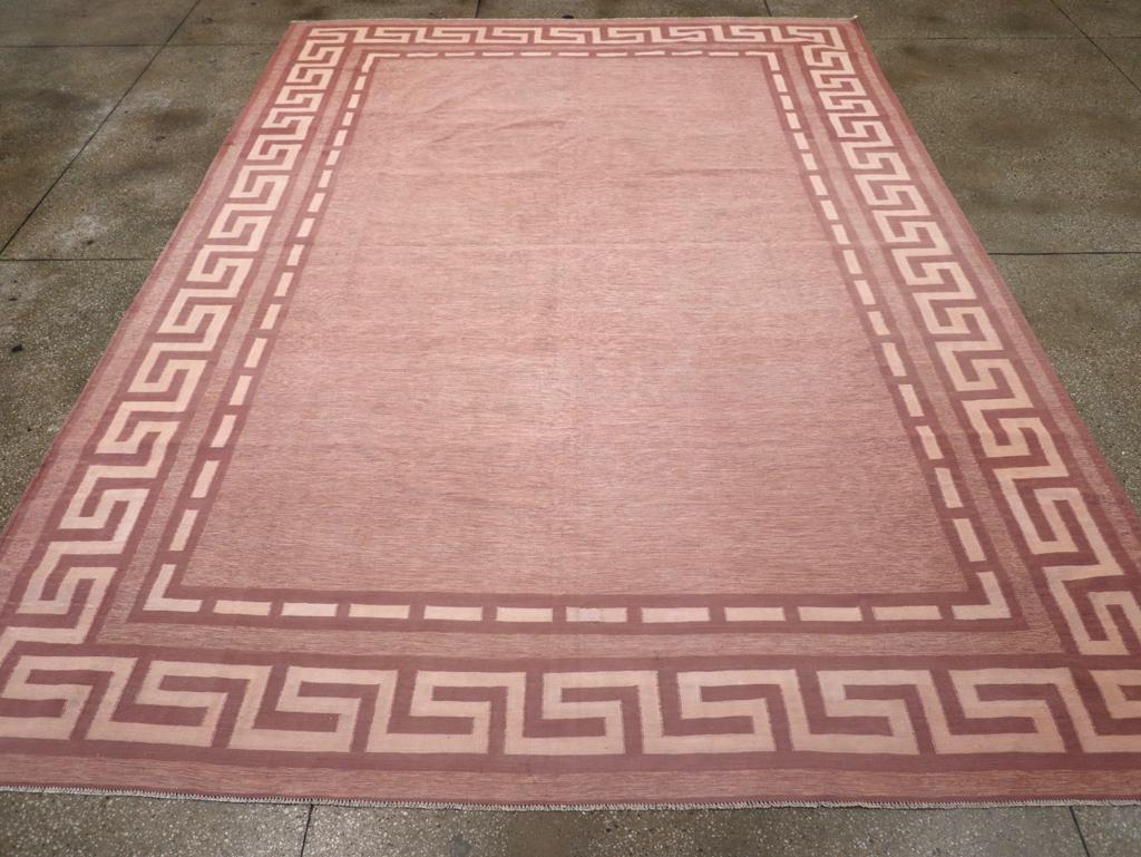 Trame in cotone con tecnica ad arazzo su una base di cotone. Semplicità moderna! Il campo marrone rossiccio, completamente semplice, è perfettamente incorniciato da un ampio bordo principale bitonale marrone e crema a chiave greca e da una striscia