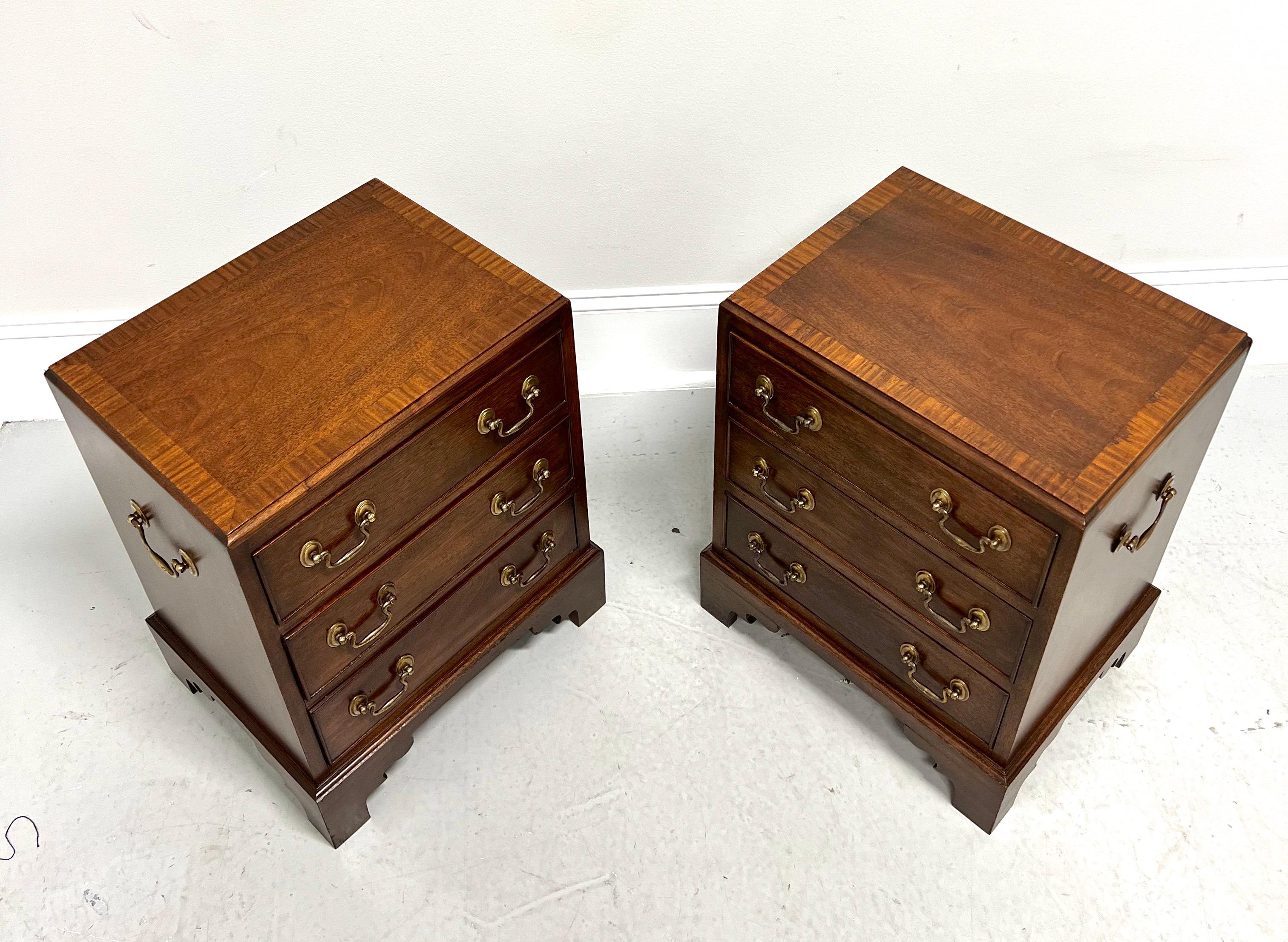 A pair of diminutive Chippendale style bedside or chairside chests, unbranded. Mahogany with brass drawer hardware & side handles, inlaid banded top with beveled edge, fully finished on all sides, and bracket feet. Features three drawers of dovetail