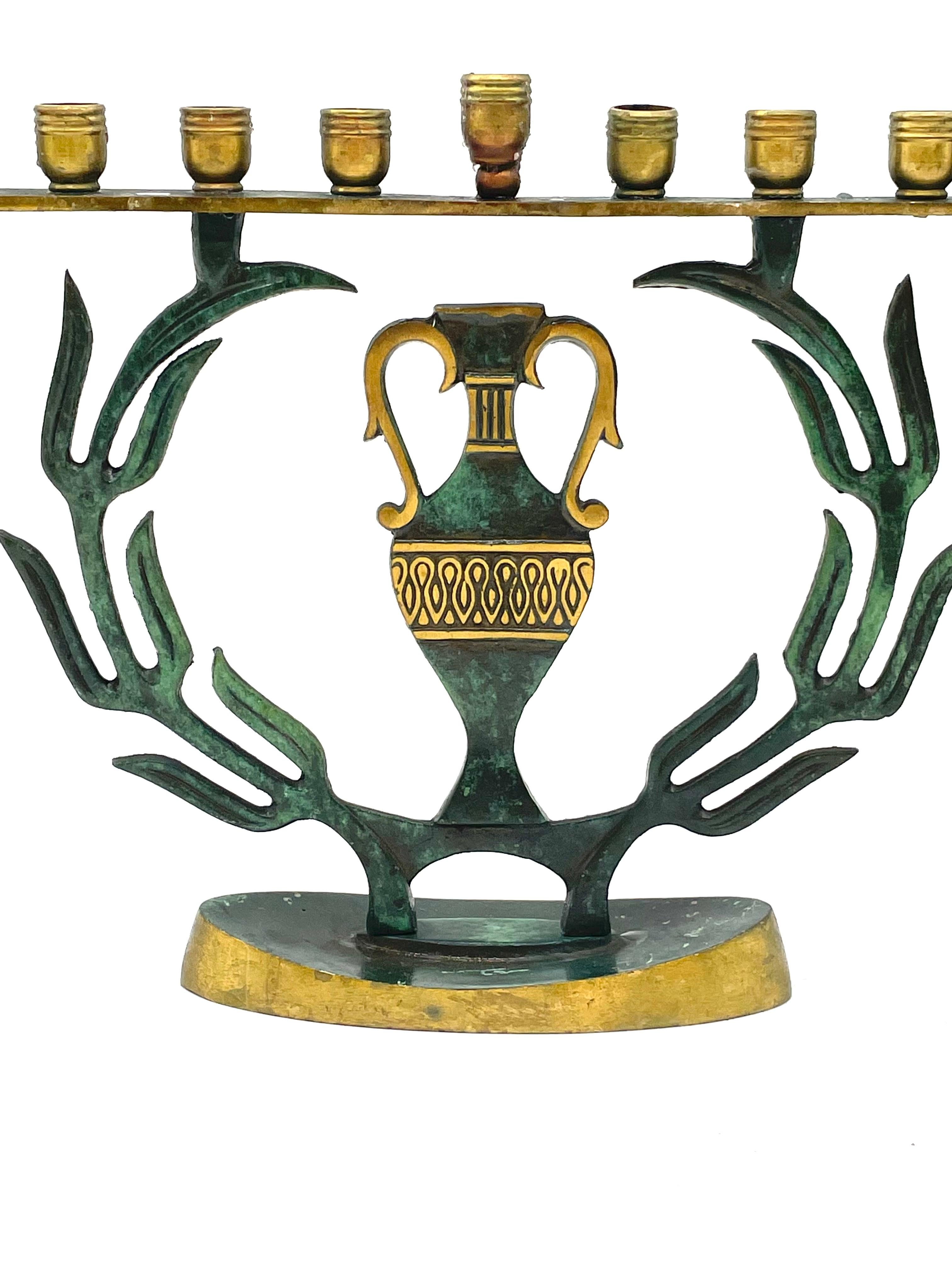 Cast brass made in Israel, circa 1950. Cast brass with green patina overlay. Jar in the middle depicts stylized patterns with gilded accents between two olive branches.
Marked on the bottom 