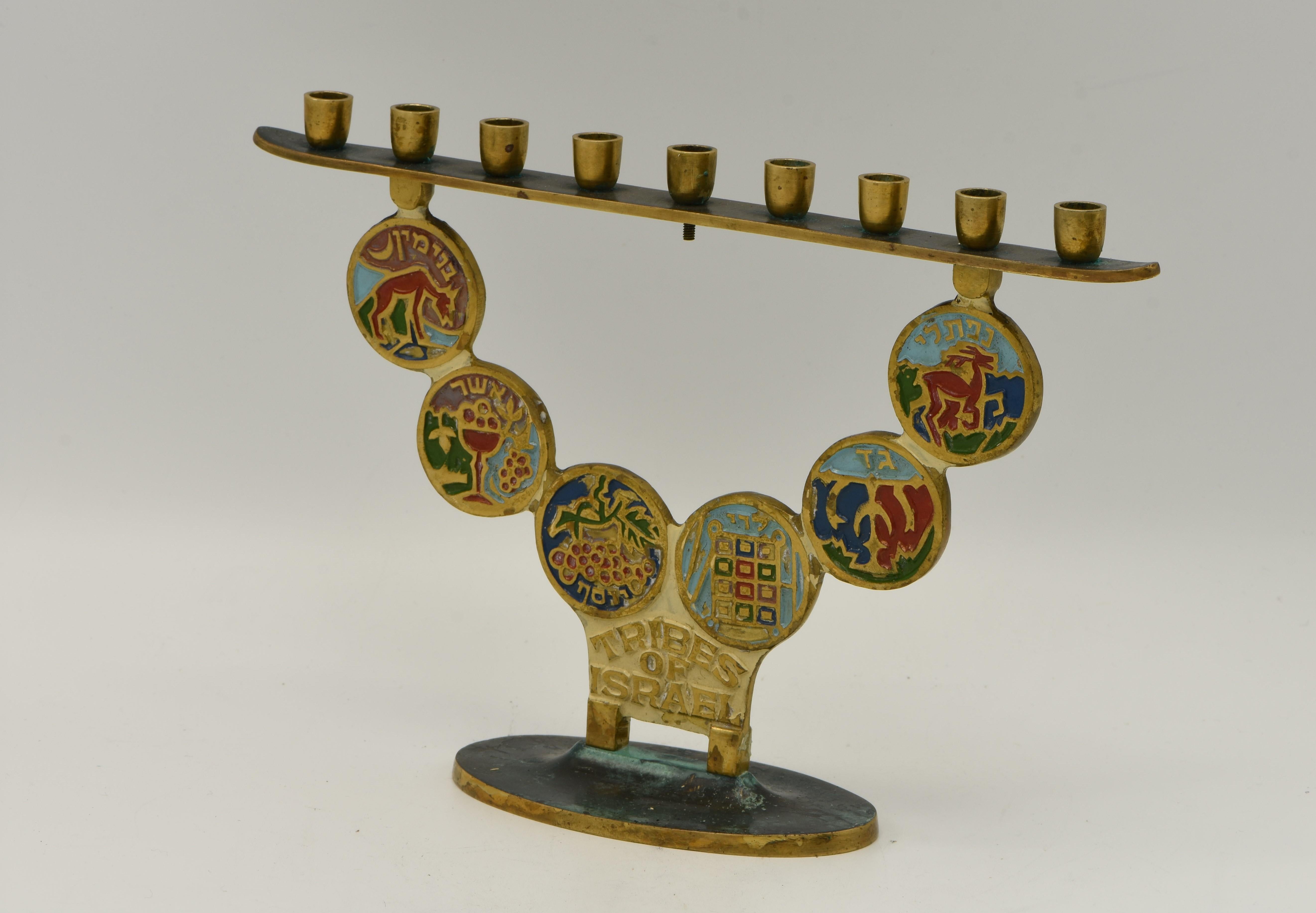 Hanukkah Lamp Menorah, brass, Israel, circa 1950.
On an oval base with six medallions depict the Tribes of Israel symbols decorated with colored enamel.
Titled in English and Hebrew 