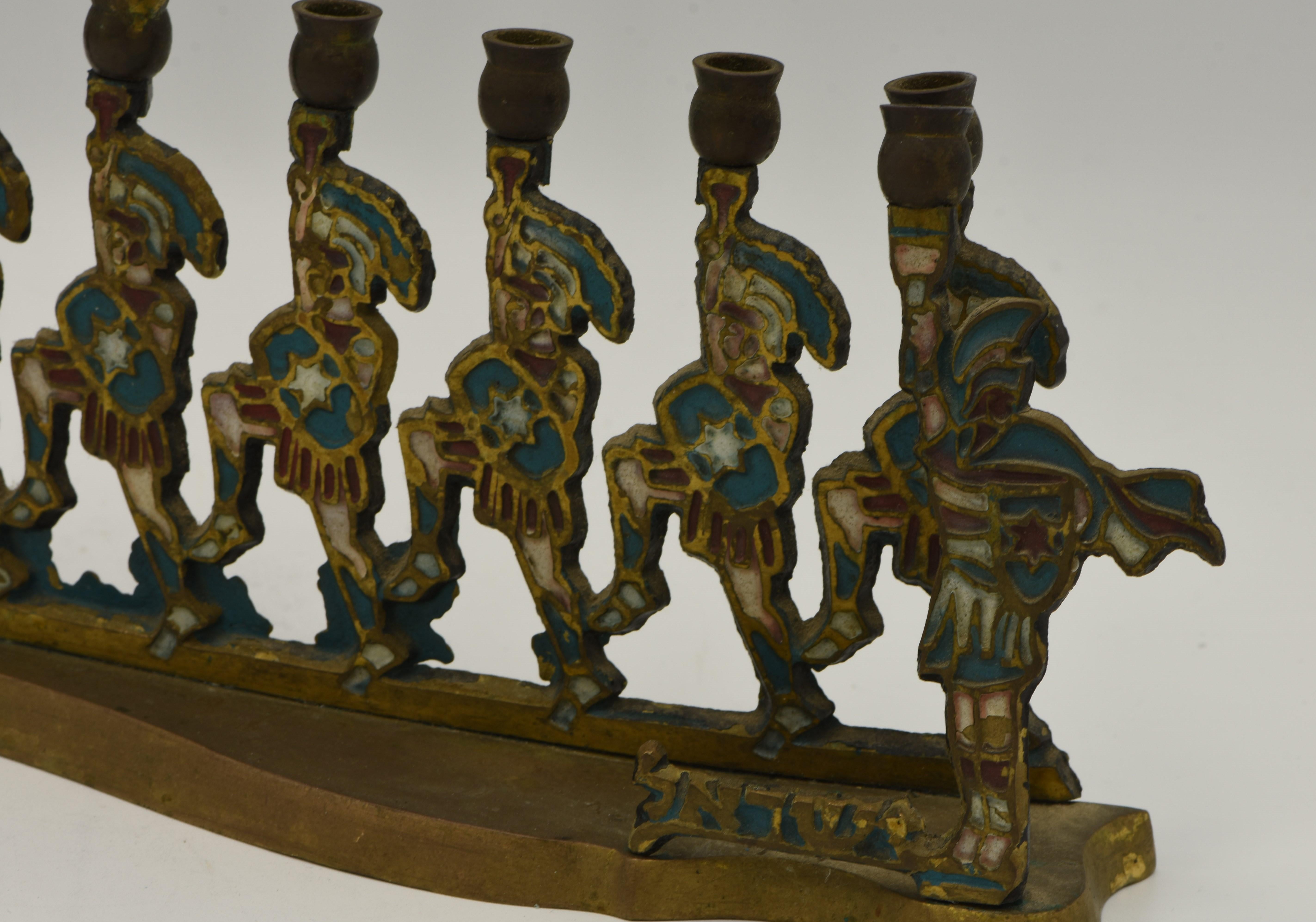 Cast enameled brass Hanukkah Lamp Menorah, Israel, circa 1950.
In a form of nine Maccabees holding the candles, the Servant light (Shamash) with the Hebrew word 