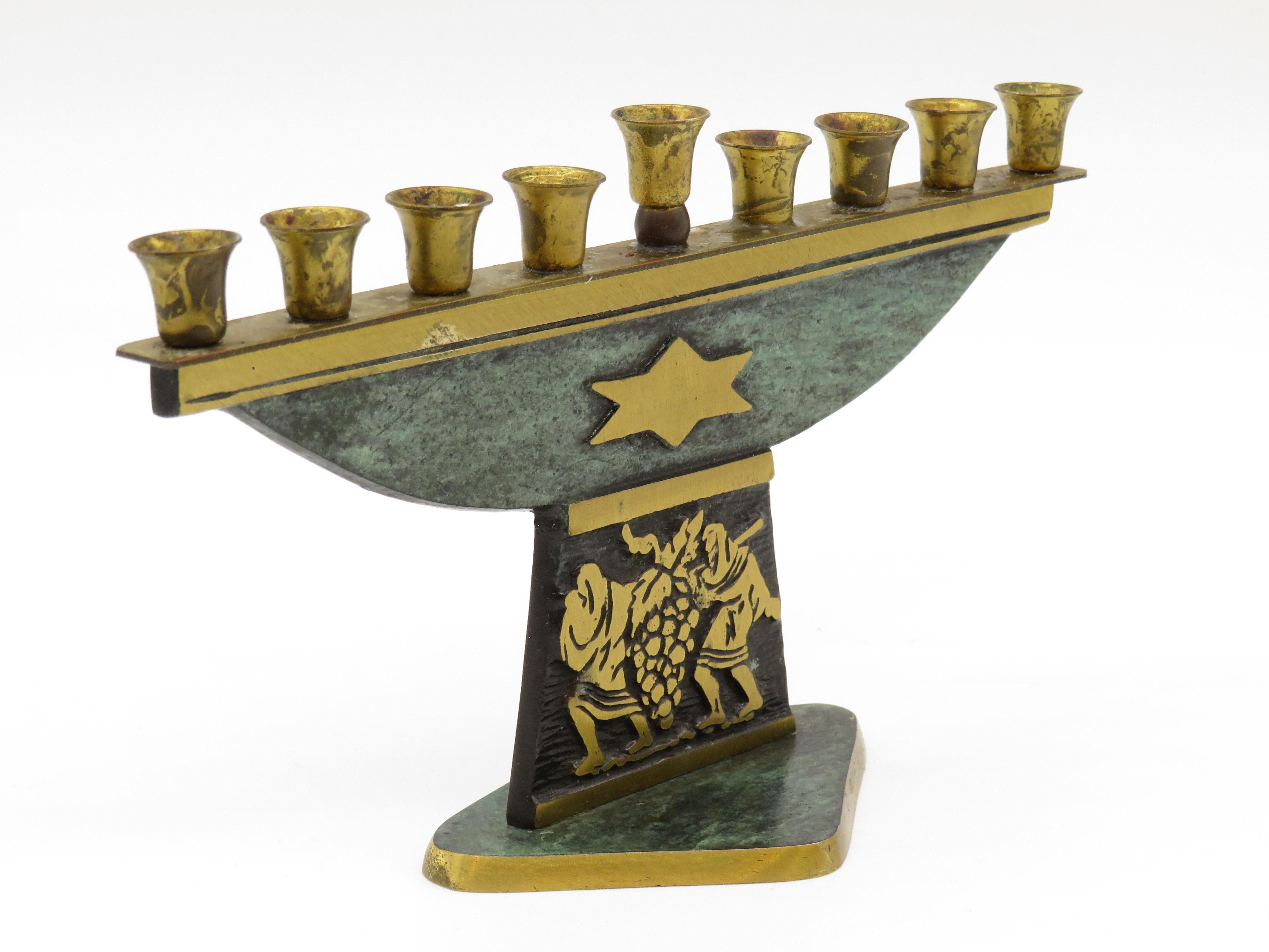 Hanukkah lamp menorah made in Israel, circa 1950s. Signed on the bottom Dayagi. Green patina overlay in the front with a bold Star of David. A detailed scene of the spices on the way to Israel is depicted. Gilded accents on detailed scene and bottom