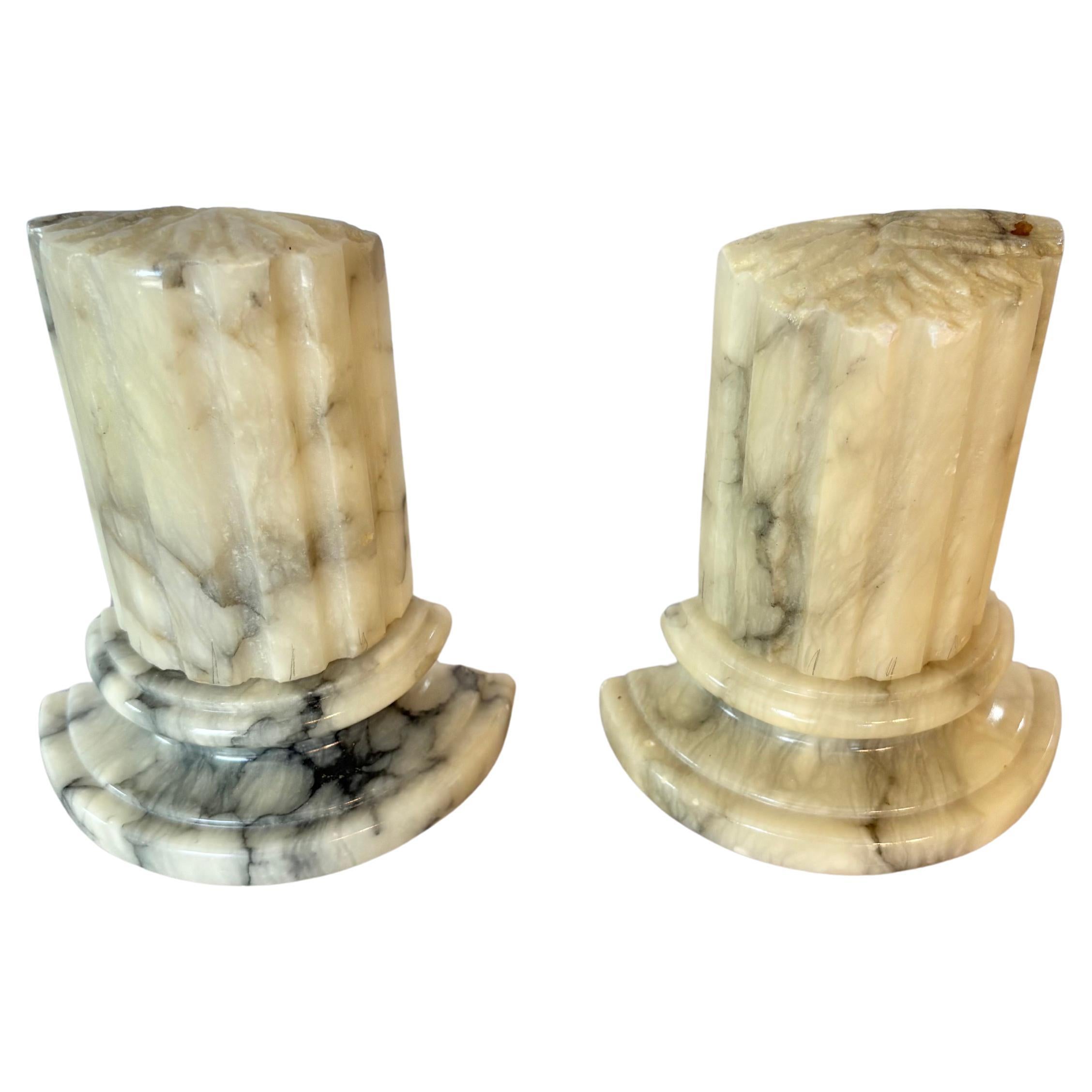 Dieses Paar Buchstützen aus der Mitte des 20. Jahrhunderts wurde Mitte 1900 in Italien von Hand im Grand-Tour-Stil aus Alabaster geschnitzt. Jede Buchstütze weist gerippte Säulen auf, die auf erhöhten, abgestuften Sockeln ruhen. Die in Form von