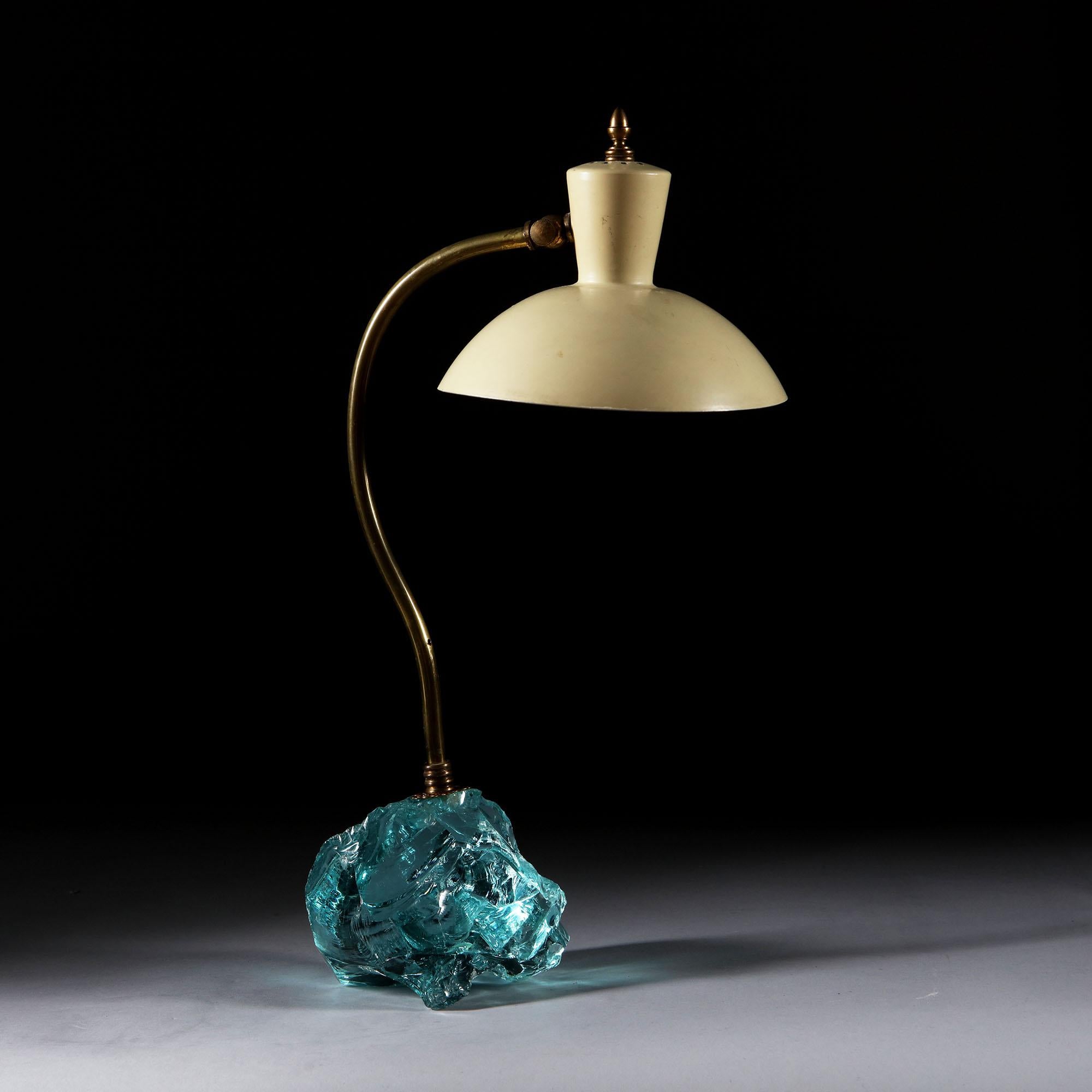 An mid-20th century, Italian desk lamp with unusual glass shard base, with curved brass stem and adjustable enamel shade surmounted with a brass finial.