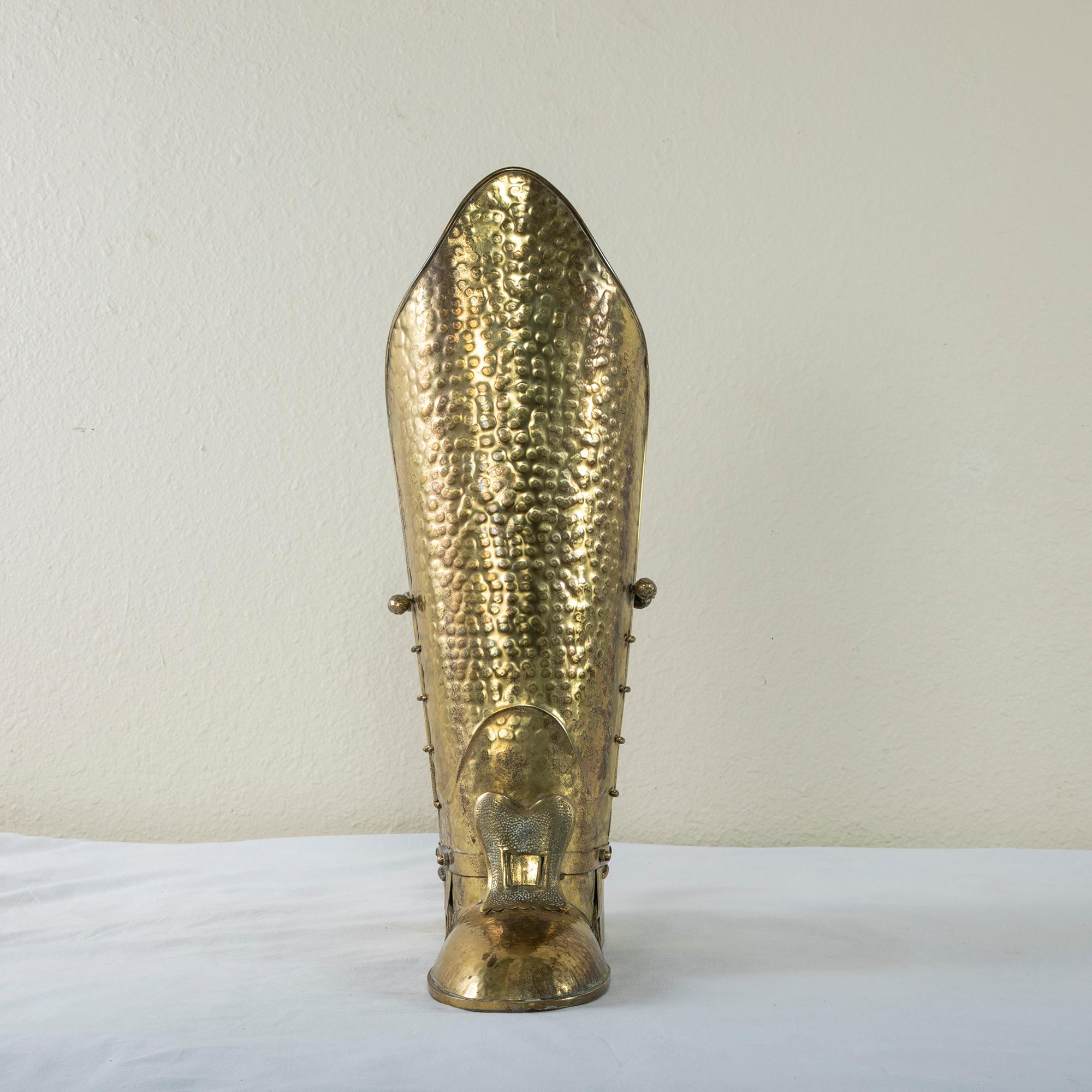 Standing at 22 inches in height, this mid-20th century hand-hammered brass umbrella stand from Italy takes the form of a large riding boot. The boot is detailed with a buckle at the front and a spur at the heel. Twisted brass lacing and straps