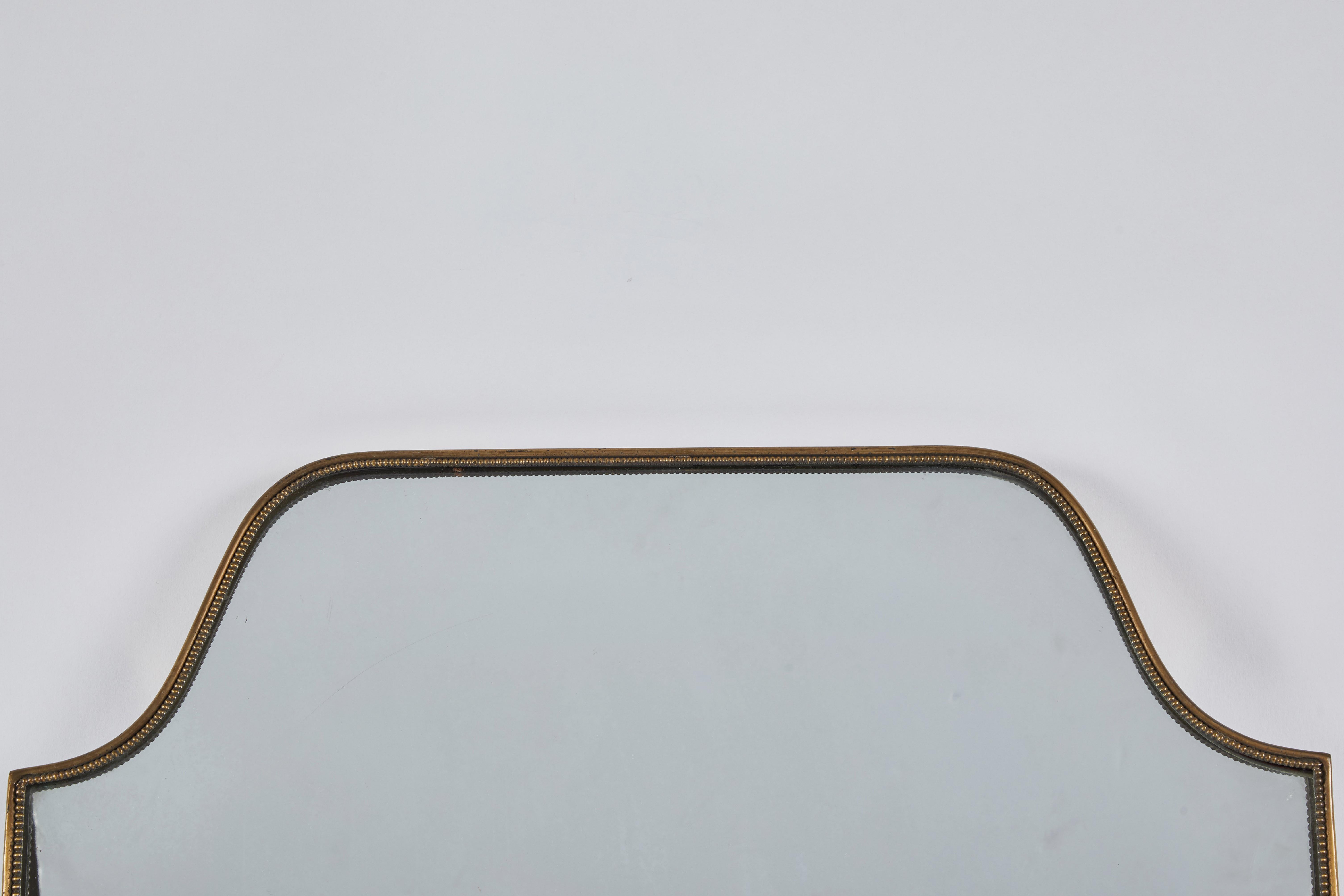 1970s Italian brass shield mirror with sweet trim and brass screw details throughout. Slightly masculine, but clean in style, the scale of this mirror allows for a variety of uses. Good overall brass condition and mirror condition.