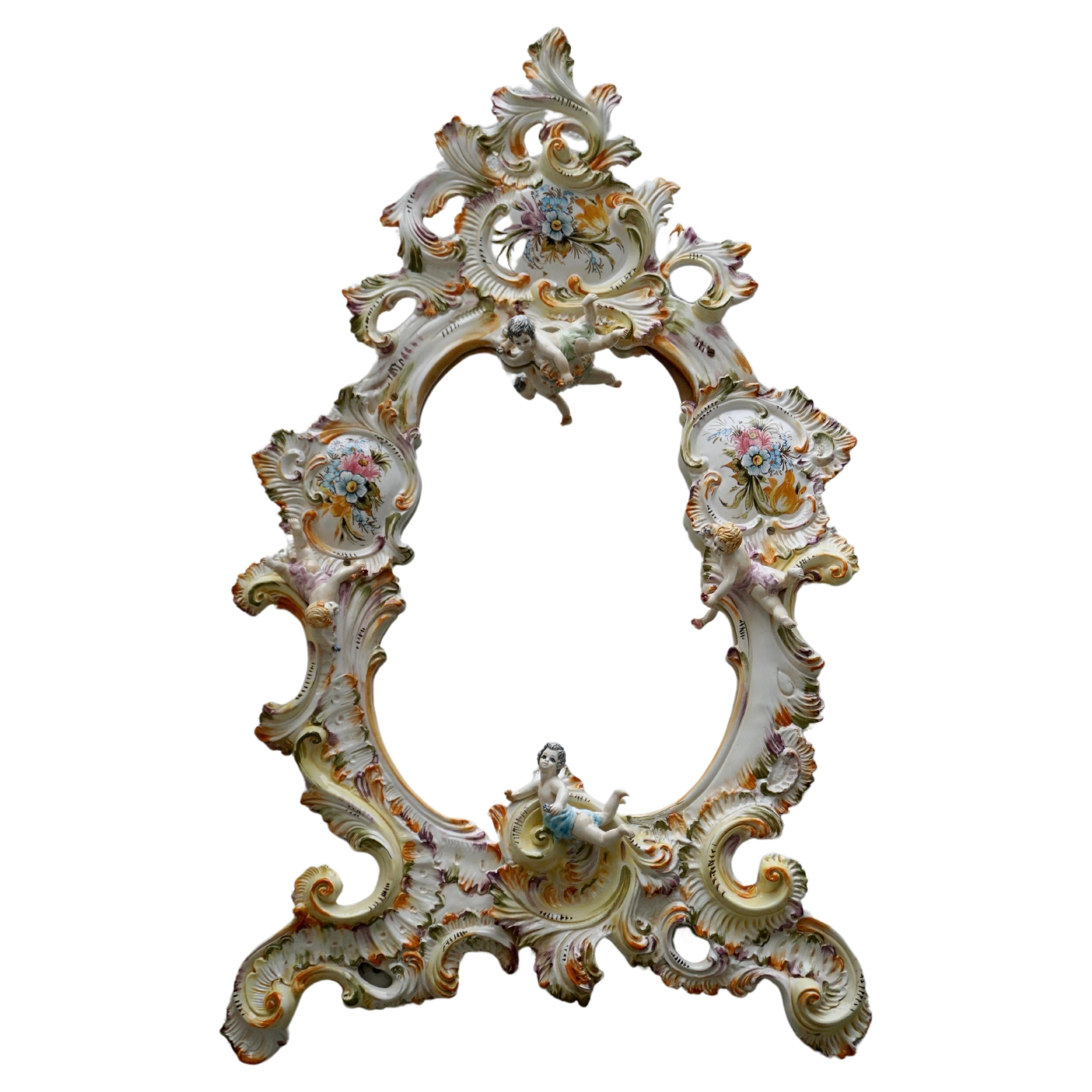 Large vintage Capodimonte style porcelain framed wall mirror and elaborately decorated with a variety of delicately crafted flowers and cherubs.
Italy, 1970s.

Height 44.8