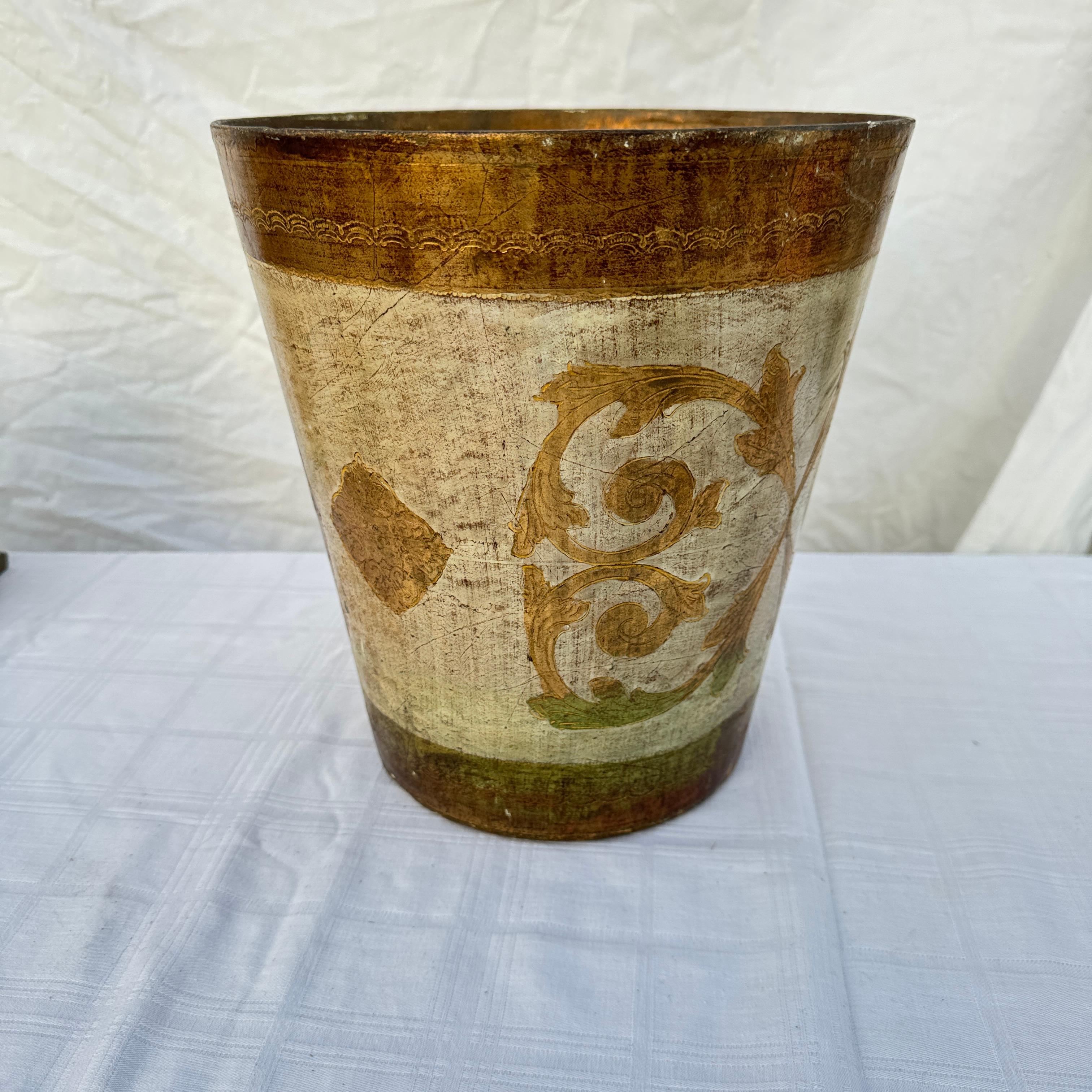 This exquisite 1950s vintage Florentine wastebasket, crafted in Italy, showcases the timeless elegance of mid-century design. Made from carved giltwood, it features an ornate floral and scrollwork motif, beautifully highlighted in gleaming gold leaf