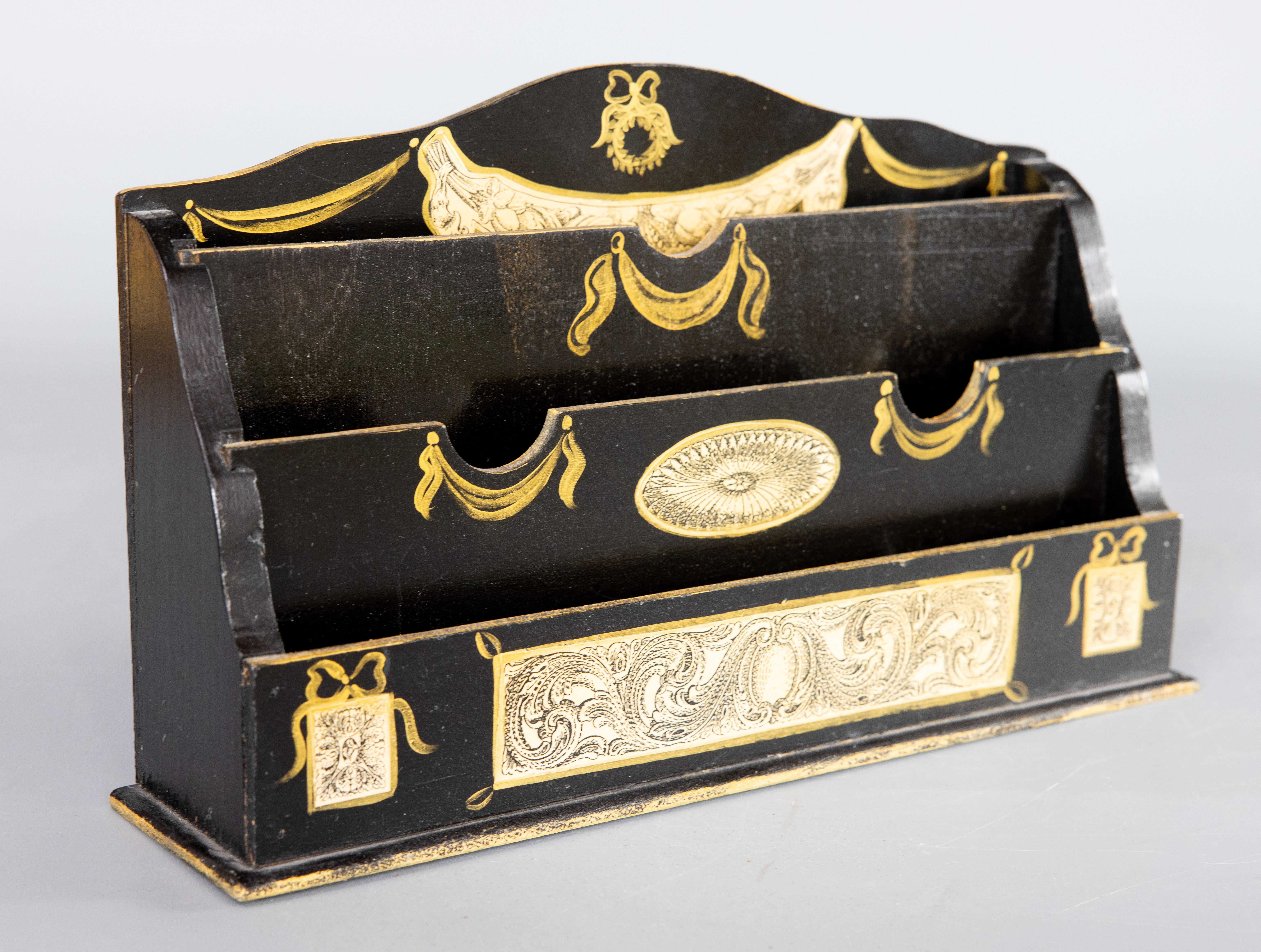 A lovely vintage Neoclassical style Italian gold and black lacquered wood desktop letter holder. No maker's mark. This stylish letter rack has three slots for letters and is decorated with ornamental découpage and handpainted gilt swags, scrolls,