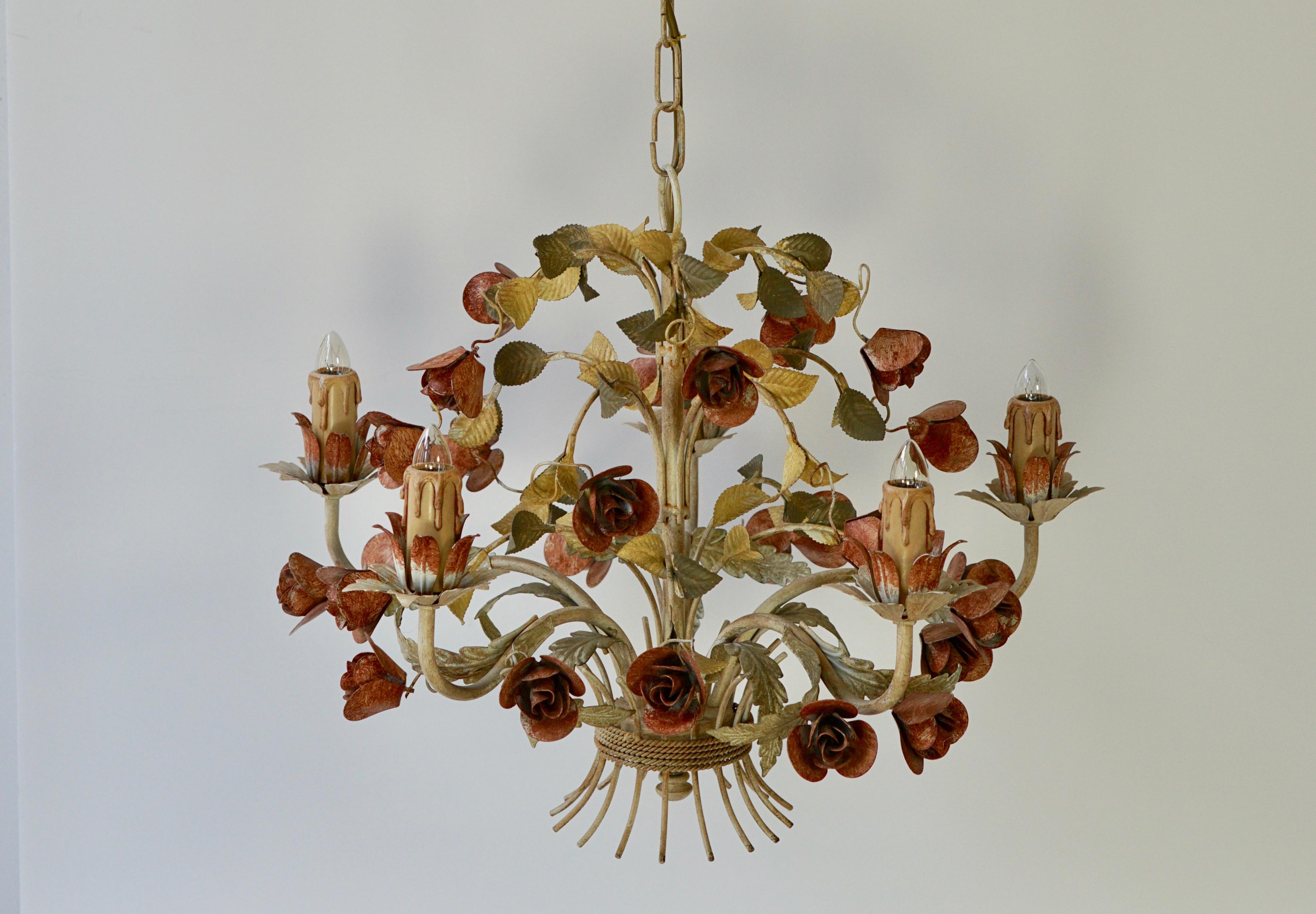 This elegant chandelier was crafted in Italy, circa 1960 -1970s. The charming hanging light fixture has five lights and is embellished with realistic flowers and green leaves. The round chandelier is in very good condition and has its original