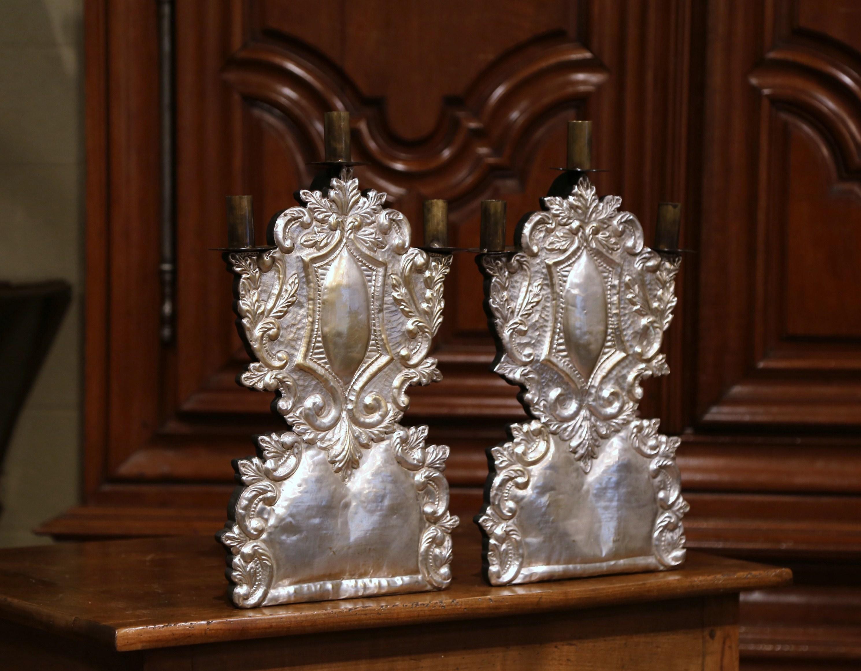 Decorate a buffet or embellish a console with this pair of elegant, Italian candelabras. Crafted in Italy circa 1950, each wooden candlestick is dressed with a silver over brass covering for an elegant, dramatic look. The light fixtures are