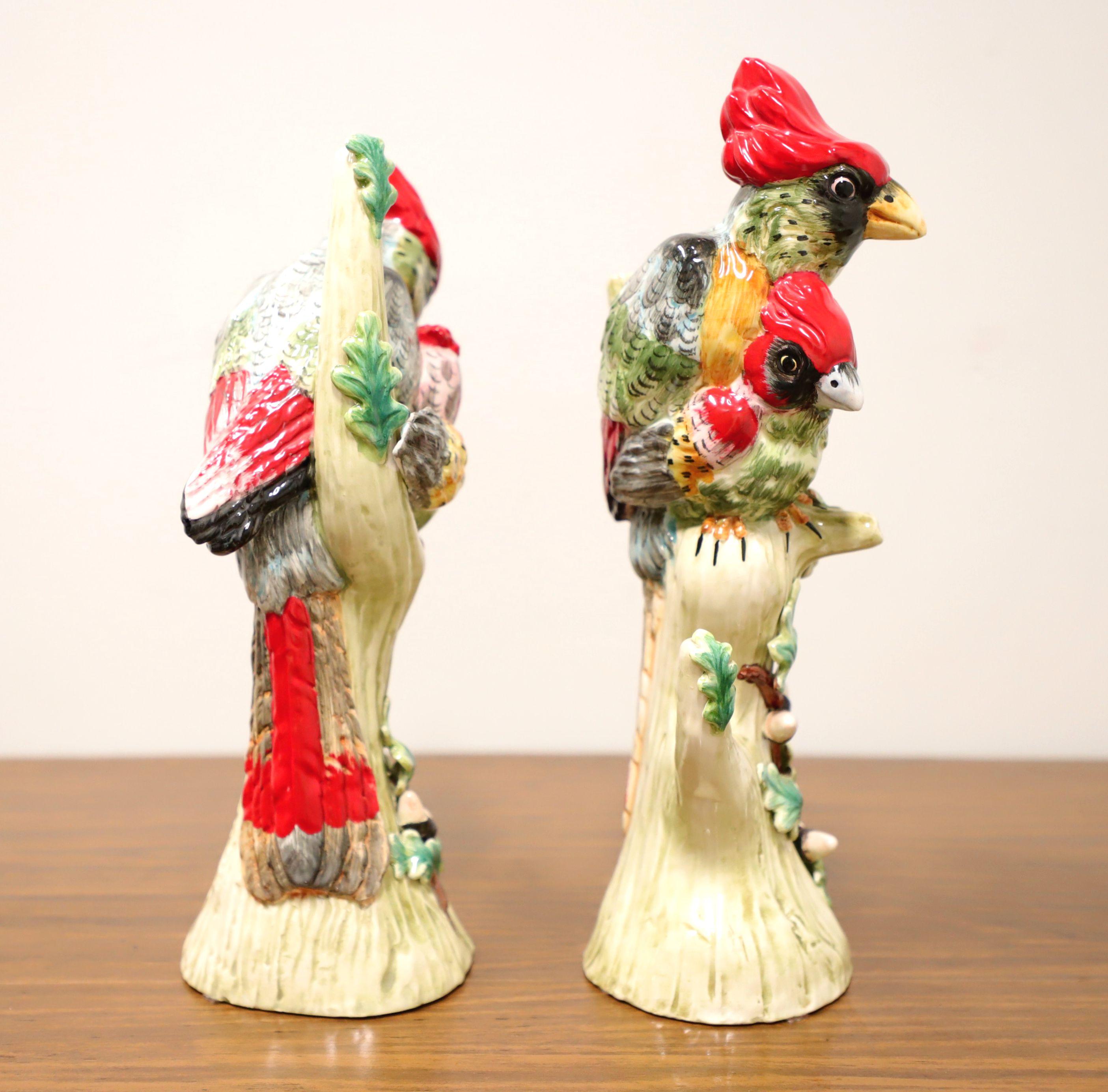 A pair of porcelain figurines depicting female cardinals on tree branches. Multi-colored porcelain of primarily red, black and shades of green, and glazed. Unsigned, artist unknown. Underside of one figurine is stamped 