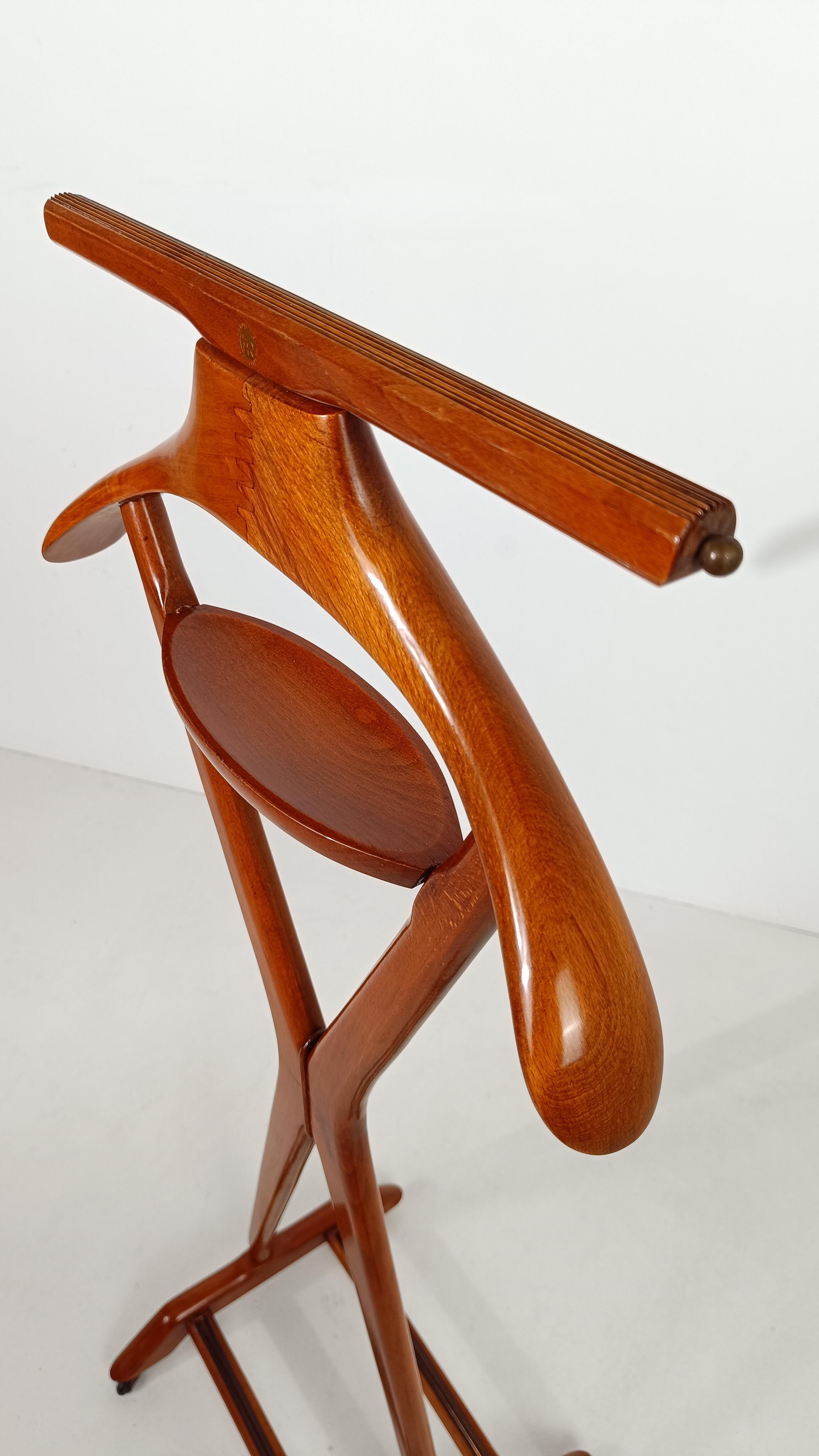 Magnifique valet de chambre fabriqué en Italie entre les années 50 et 60 par la société historique Fratelli Reguitti en bois de hêtre massif teinté cerise avec détails en laiton.
Le design de ce splendide porte-vêtements de chambre à coucher est