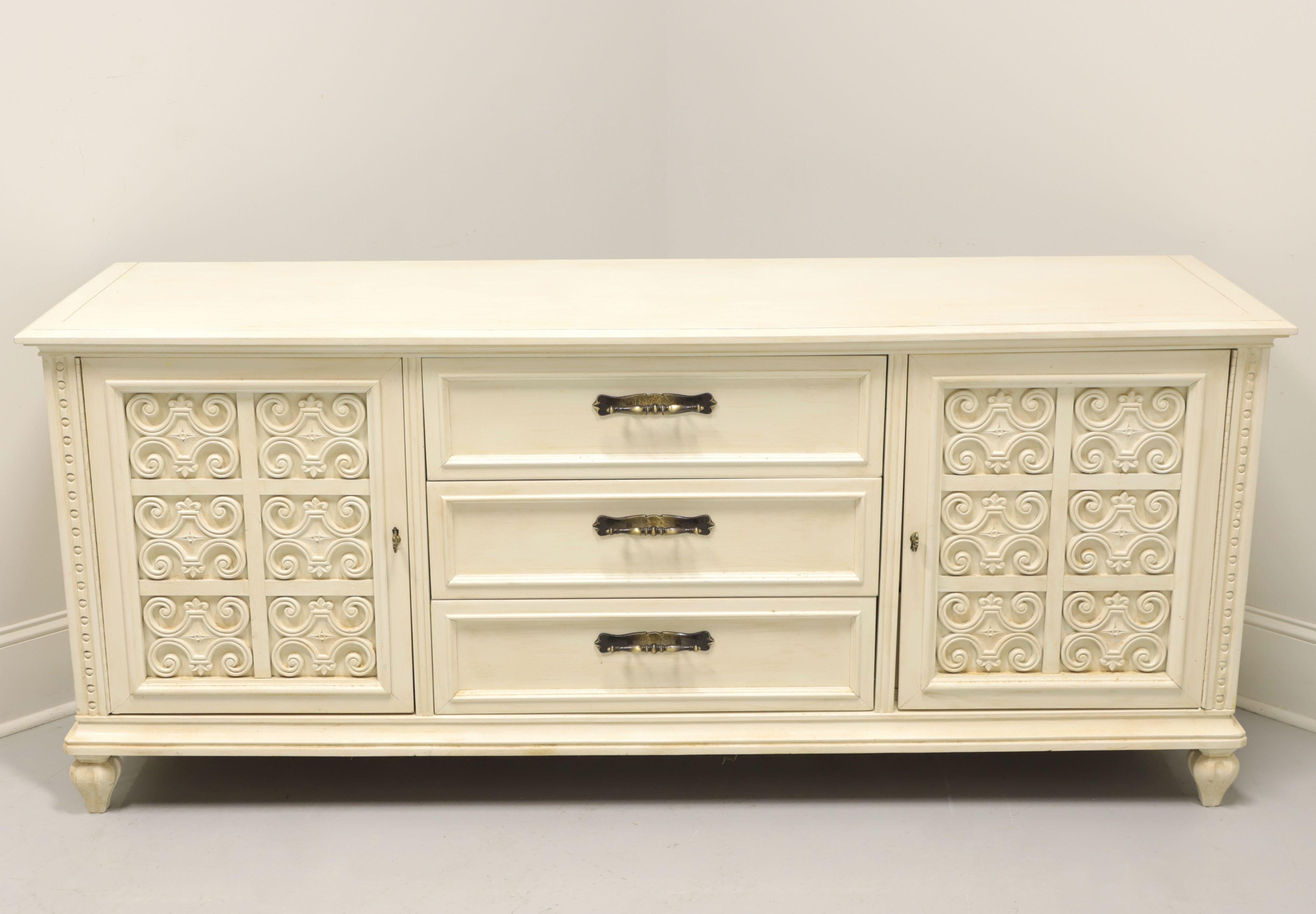 A Spanish style triple dresser, unbranded, similar quality to Drexel or Henredon. Solid hardwood painted ivory, slightly distressed, brass hardware, banded top, carved front corners and turnip feet. Features nine drawers of dovetail construction,
