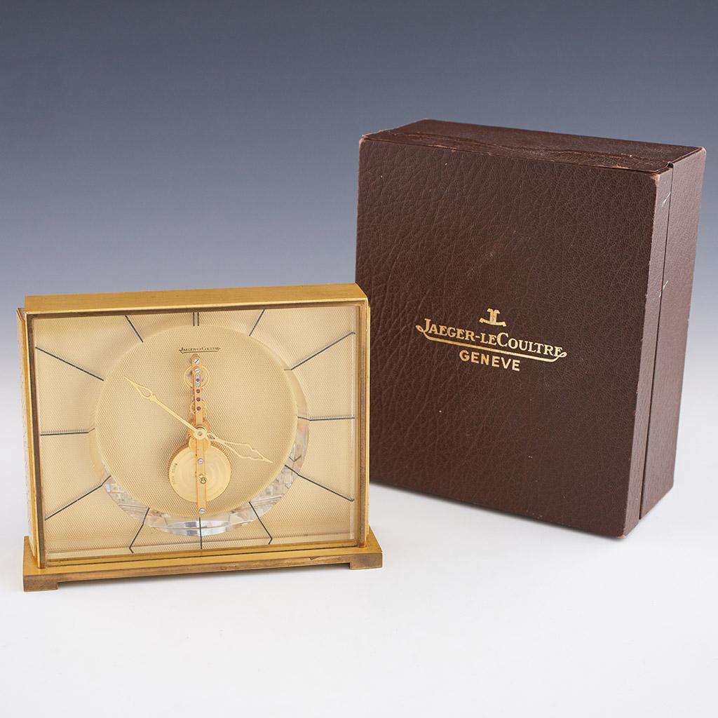 A mid 20th century mantel clock by Jaeger LeCoultre. Gilt brass framed with glass case and inset textured brass background. Original 8 day movement in full working order with original box. 

Dimensions: H 12.5cm W 16cm D 4.5cm

Origin: Swiss

Date: