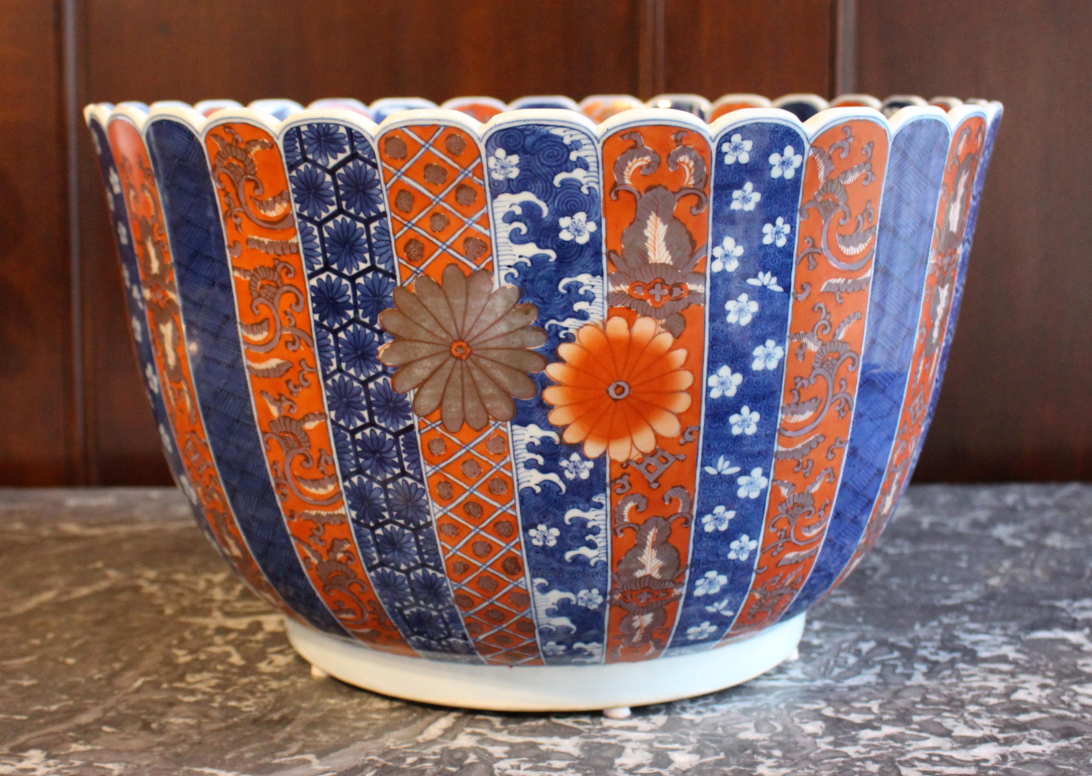 Mid-20th century Japanese Imari Punch Bowl. Grand, deep scale with lobed rim, surrounded by conforming panels of diapered motifs. Large orange & gilt chrysanthemums decorate with exterior & interior; the inner bottom is one huge flower. 15.75