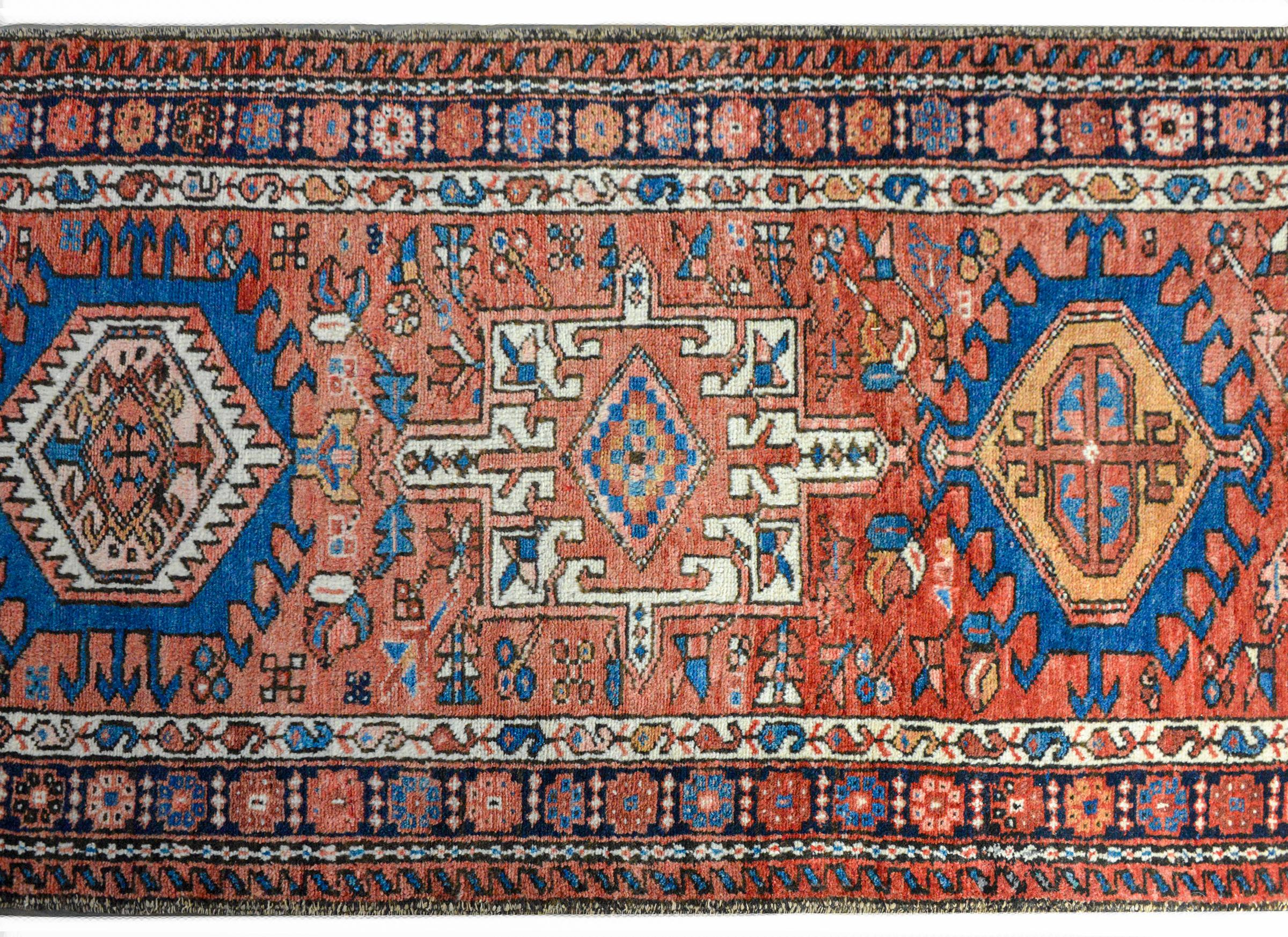 A wonderful mid-20th century Persian Karadja runner with several stylized floral medallions woven in myriad colors including indigo, pink, white, crimson, and gold, amidst a field of more stylized flowers against a crimson background. The border is