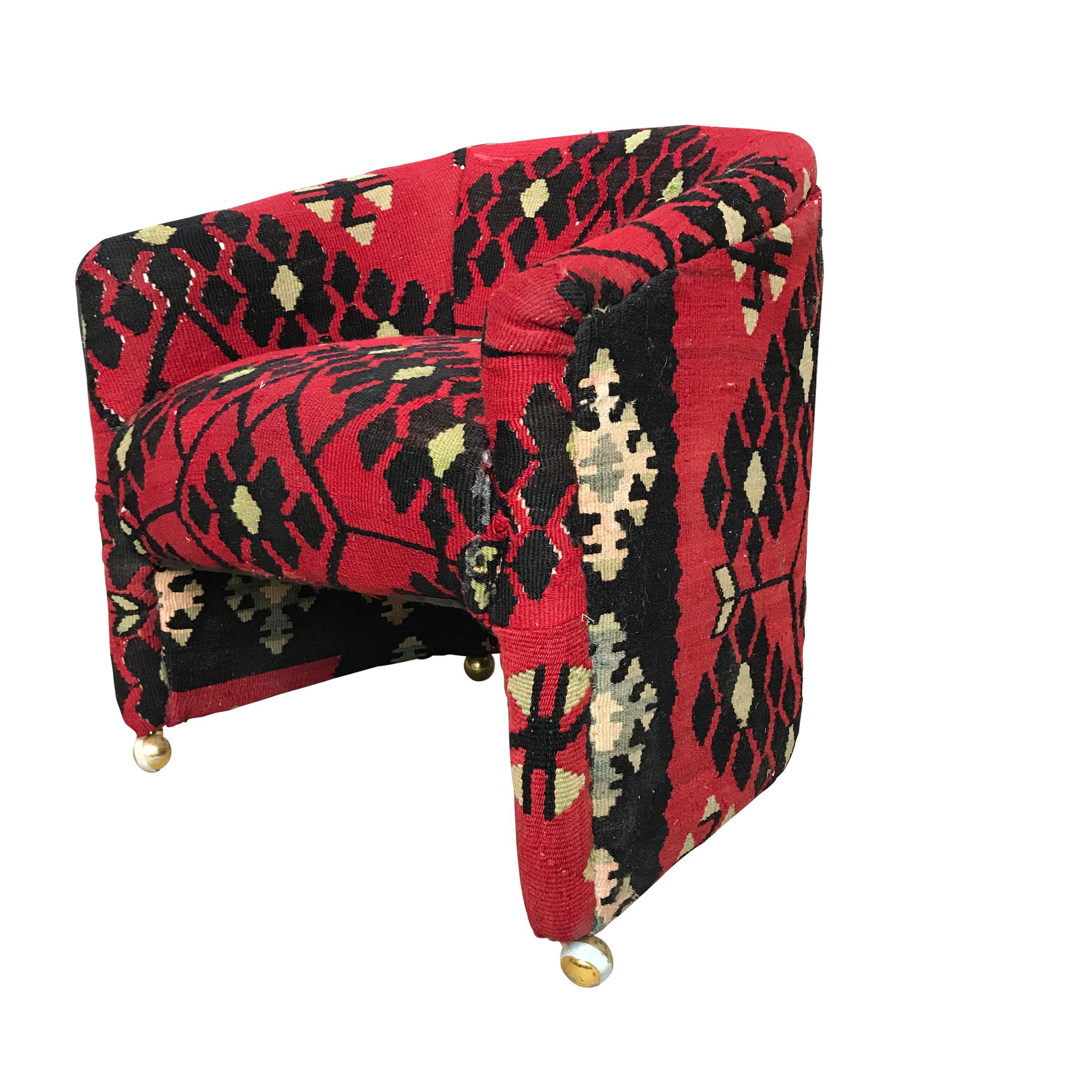 A wonderful mid-20th century American club chair upholstered in a vintage wool crimson, black, and gold Kilim rug. The chair sits on its original brass casters.