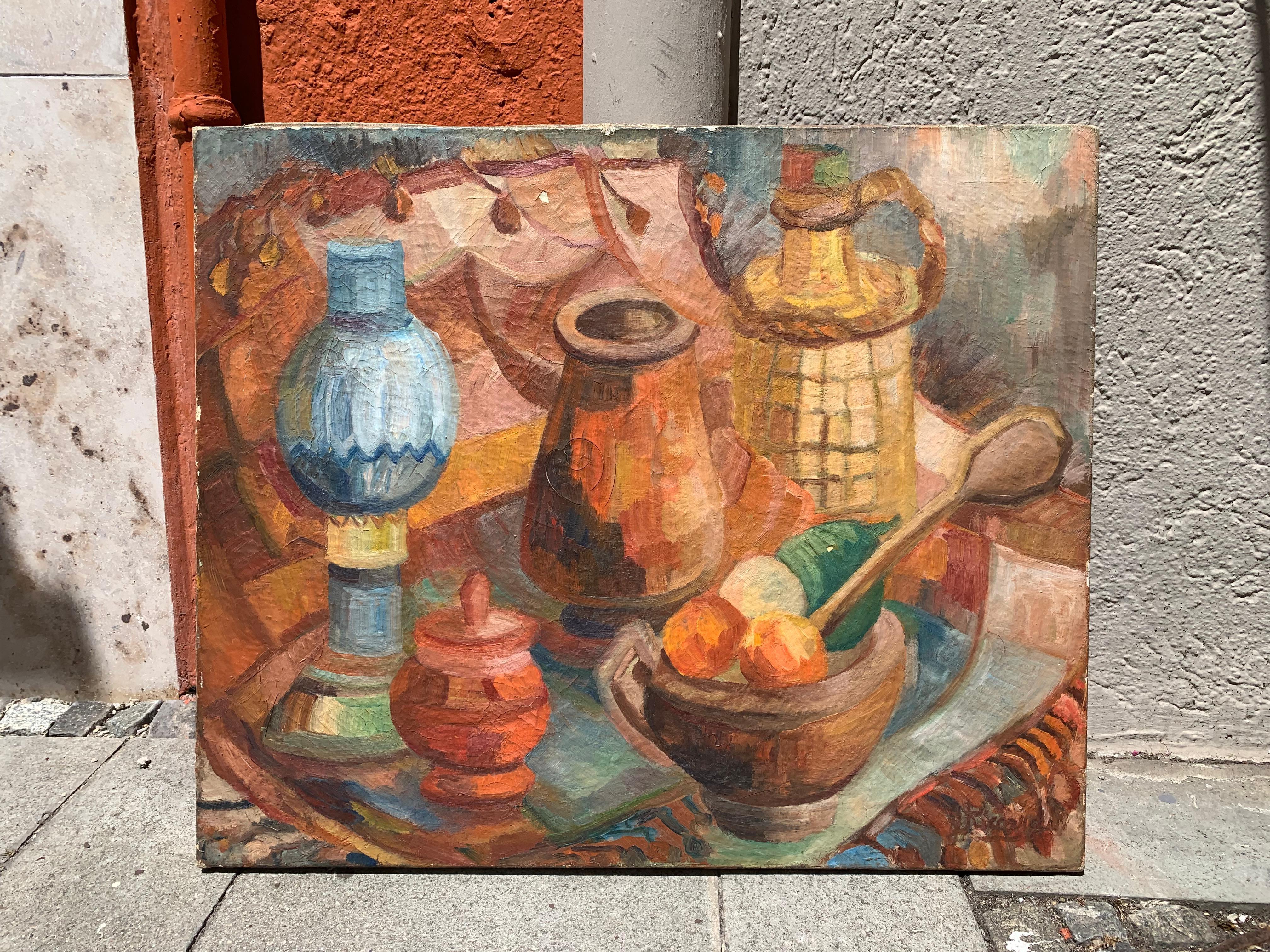 This cheerful and bright coloured kitchen still life has been painted in the mid-20th century. It was painted with oil paints on to canvas.
We see a petroleum lamp, a wine bottle, a bowl of fruits, a mortar, a wooden cooking spoon, a small lidded