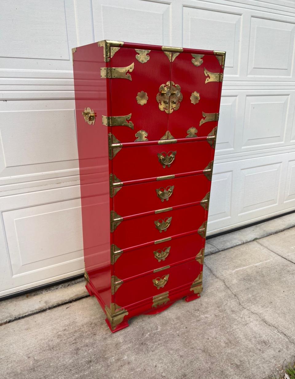 Mid 20th century brass mounted red lacquered lingerie / tansu campaign high chest with profuse engraved brass butterfly and medallion mounts, two blind doors revealing 4 small fitted interior upper drawers and 2 longer drawers over 5 full lower long
