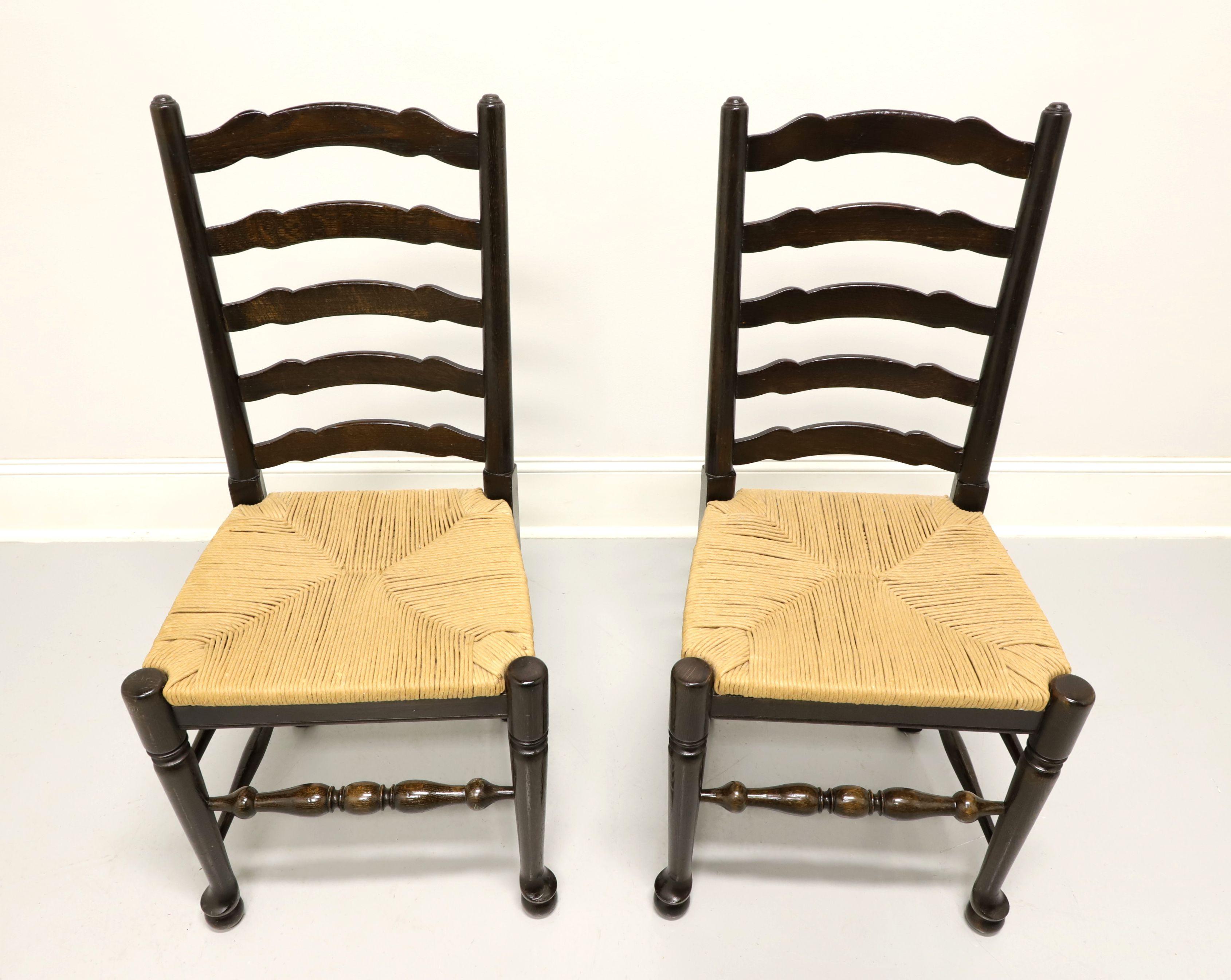 A pair of cottage style dining side chairs, unbranded, similar in quality to Ethan Allen. Walnut with carved ladder back design, rush seats, turned legs and stretchers. Made in the USA, in the mid 20th century.

Measures: Overall: 19 W 18 D 39.5 H,
