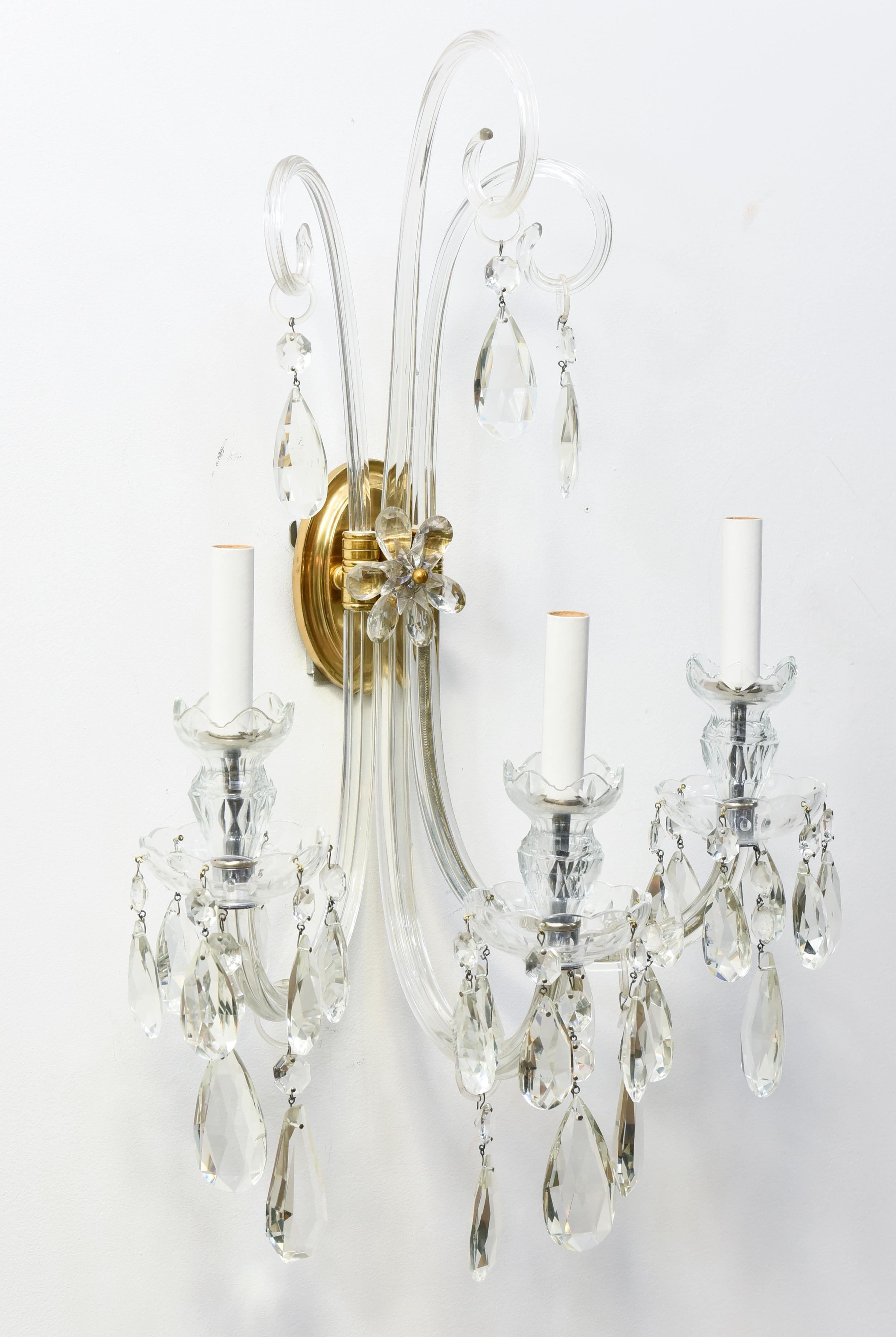 Crystal and brass sconces in the style of Lafount. two arm sconces with Brass backplates. Crystal prisms decorate the backplate like a flower.