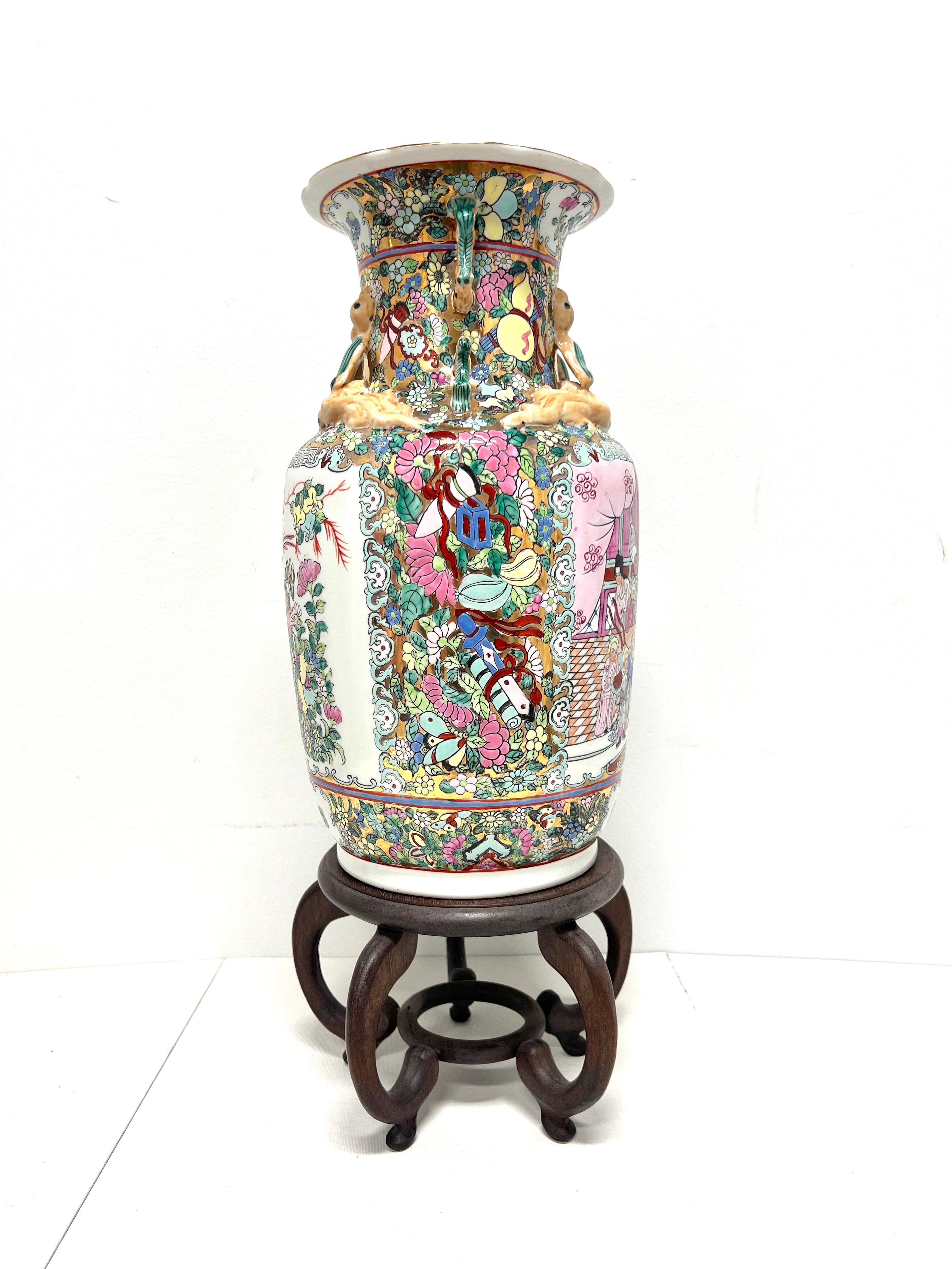 A Mid 20th Century Asian style decorative porcelain vase with stand, unbranded. A beautiful multi-color porcelain urn shaped vase with hand painted Chinoiserie scenes, a textured finish, and a separate decoratively carved round elevated wood stand.