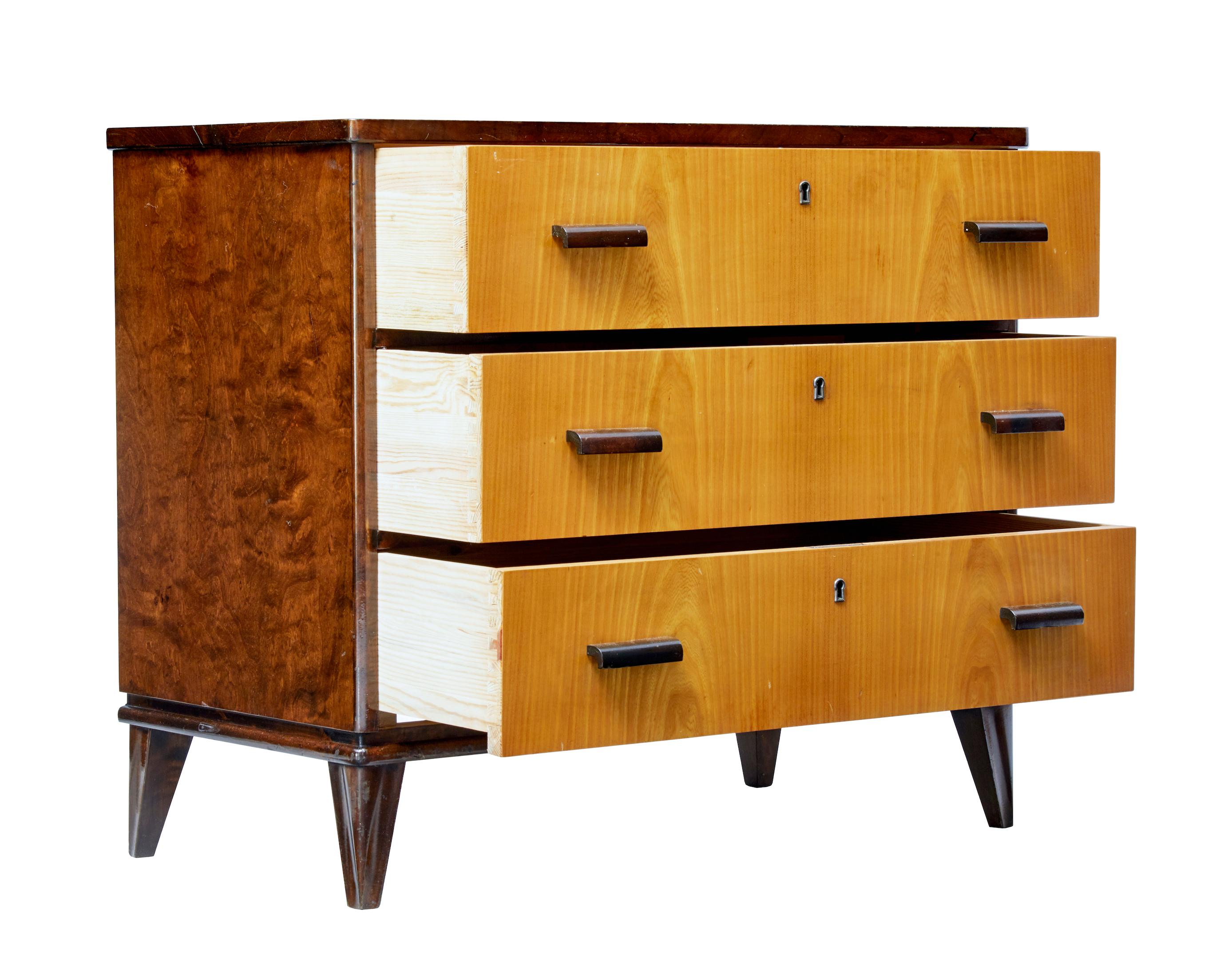 Good quality late art deco chest of drawers, circa 1950.

Three drawers with golden elm veneer which provides a striking contrast to the dark stained birch frame. Shaped wooden handles to the drawer fronts.

Burr birch sides and top surface.
