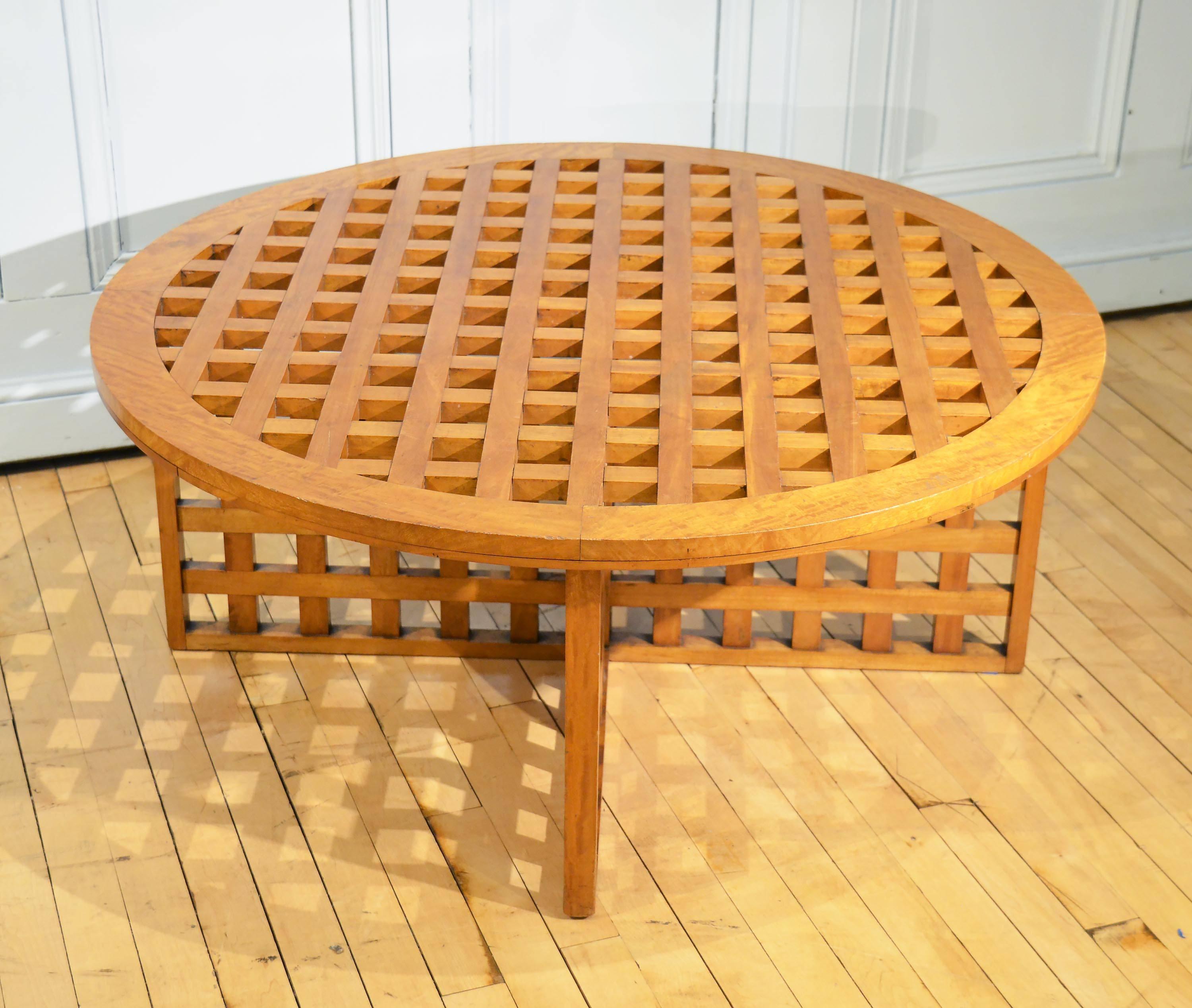 This lovely lattice design satinwood table is English and mid-20th century. It is a very sturdy and solid piece that features an unusual styled cross formed base. It measures 39.1/2 in - 101 cm in diameter and 16 in - 41 cm in height. This well