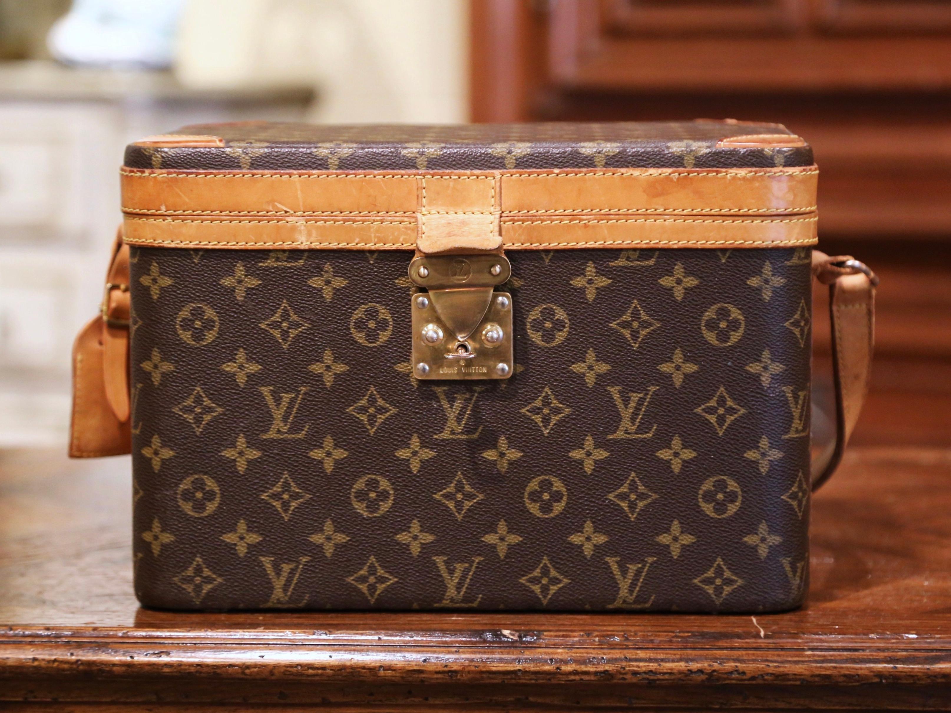 Decorate your master bath with this elegant vintage cosmetics case by Louis Vuitton; crafted circa 1970, the decorative Vuitton trunk with shoulder strap, features monogram canvas with brass fitting, inside beige fabric with clear plastic bottom,