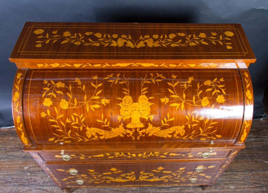 This elegant Louis XVI marquetry desk features most notably an exquisite floral design on the front, interior, and sides. The piece dates back to the mid 20th century and is known as a ‘bureau de cylindre,’ or cylinder desk, pertaining to the