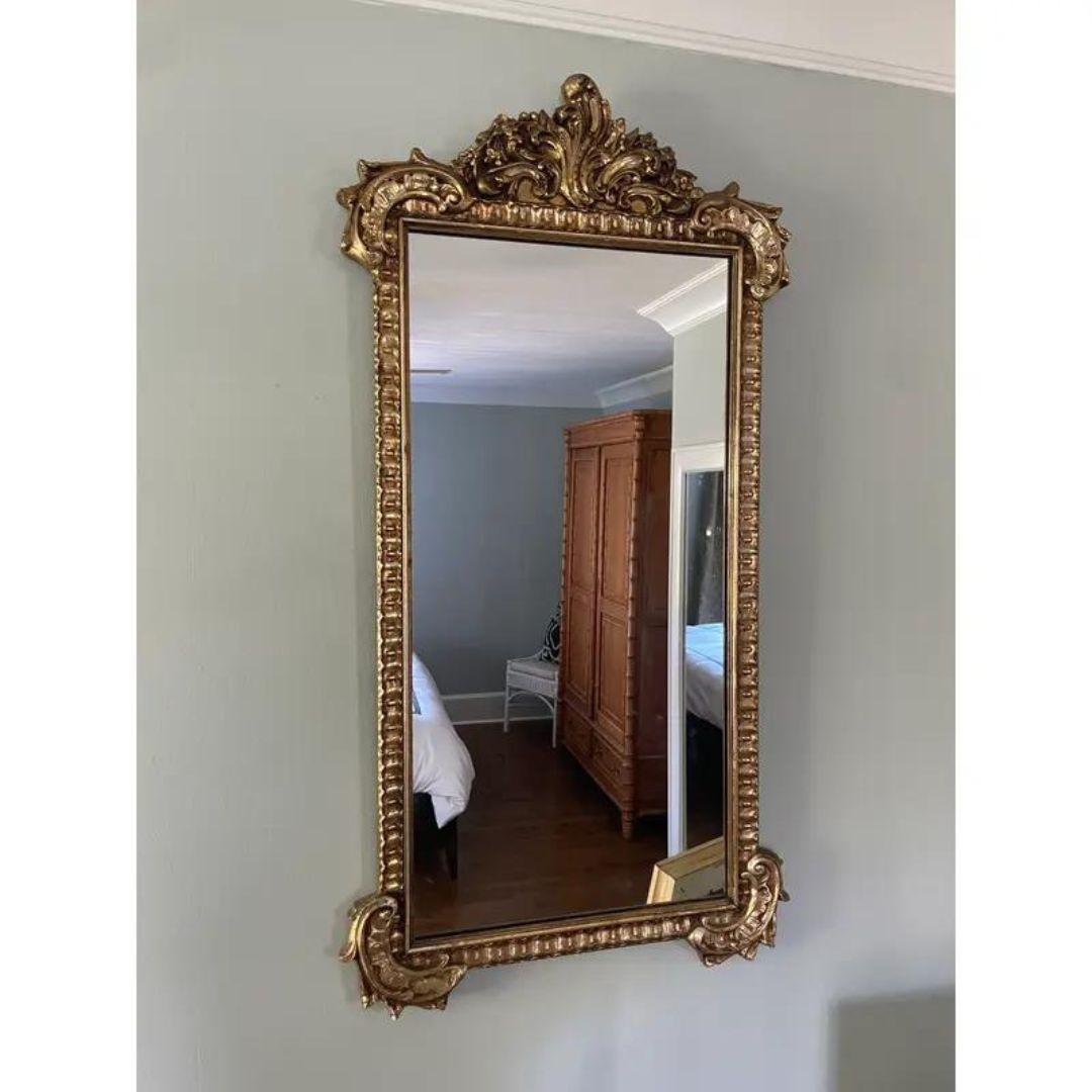Elegant Large and heavy Louis XVI style gilt wood mirror in excellent vintage condition with sturdy hanging wire on the back. Features carved wood with decorative gold/gilt, leafy embellishments all around. High-quality piece. Beautiful, unique